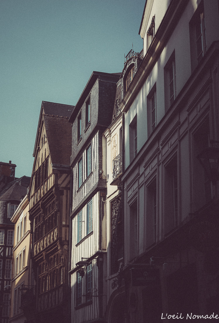 Perspective d'une rue à colombages à Rouen, jeux d'ombres et lumière douce, atmosphère historique.
