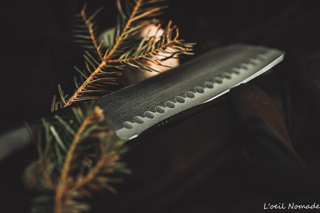 Packshot produit artisanal : couteau de cuisine en acier avec focus sur le tranchant de la lame, mise en scène épurée soulignant la qualité du métal.