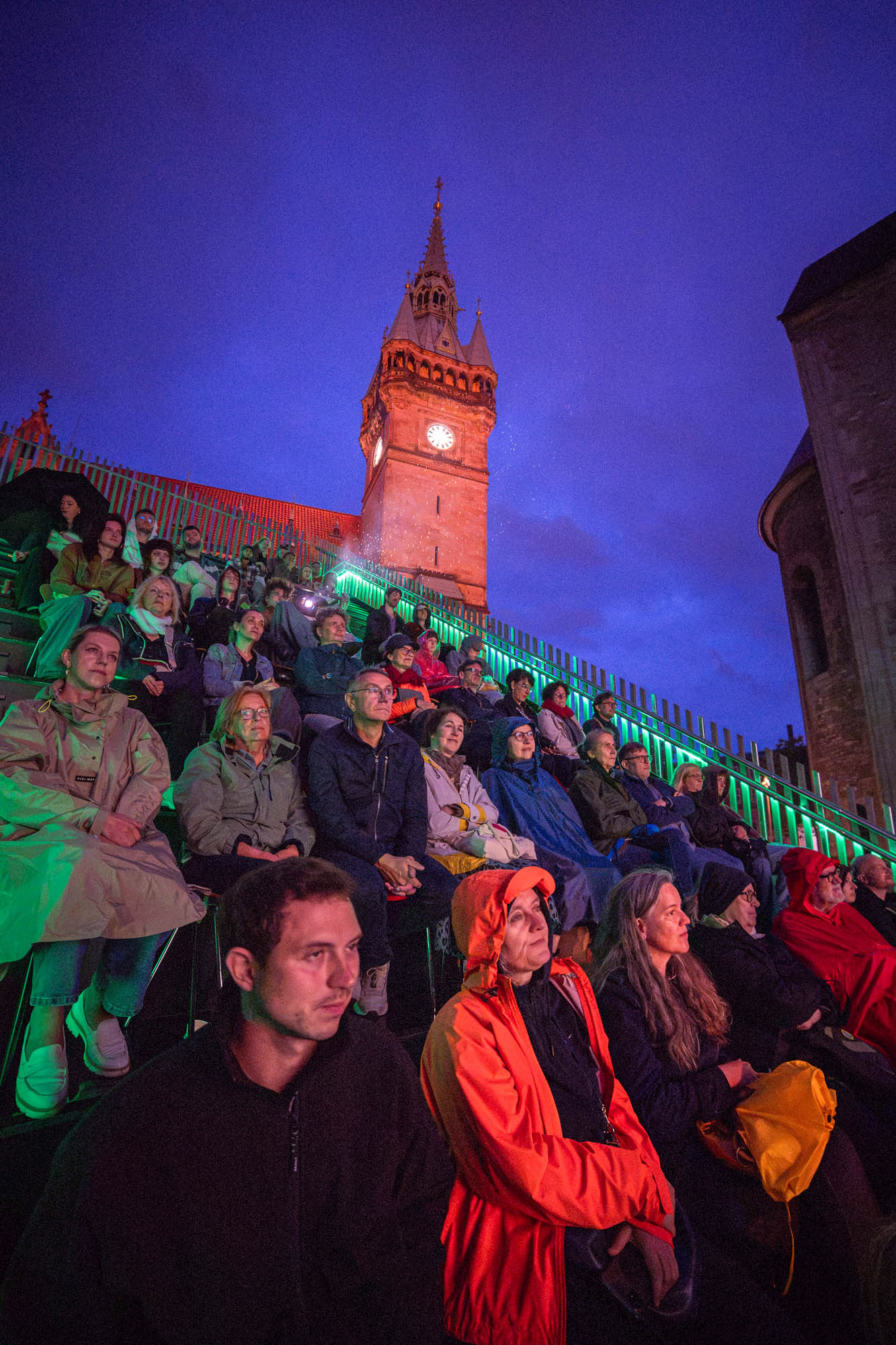 Audience watching short movies sitting on the Architecturepavillion Architekturpavillon at the Burgplatz watching the presentation of Braunschweig Filmt.