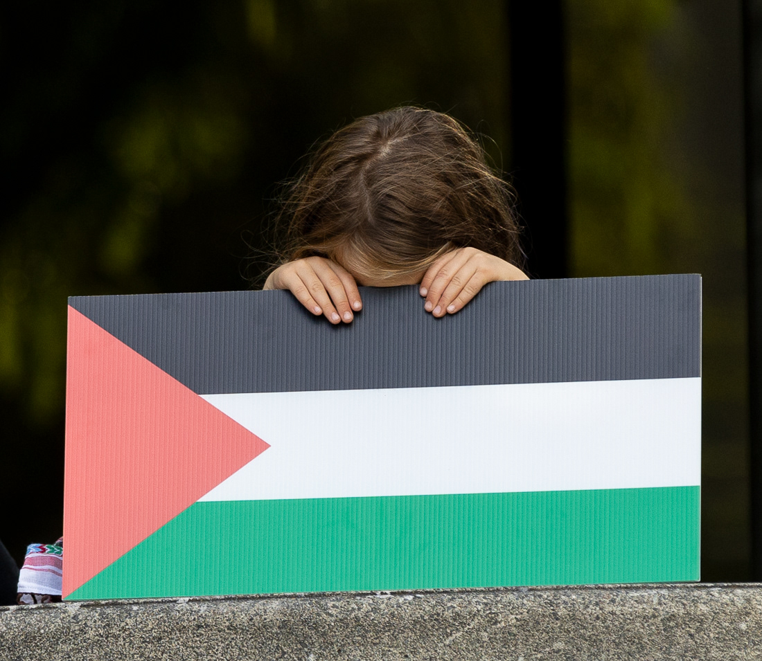 Sigrun Trewe holds a Palestinian flag sign in from of their face at the demonstration on Sep. 23, 2024. People gathered at the Wayne L. Morse Free Speech Plaza in support of the "Eugene 19"—a group of protesters who were arrested and charged as a result of a previous protest which blocked off a portion of I-5—and calling for their charges to be dropped. | Shot for Emerald Media Group | 1/1000 f/4 ISO400
