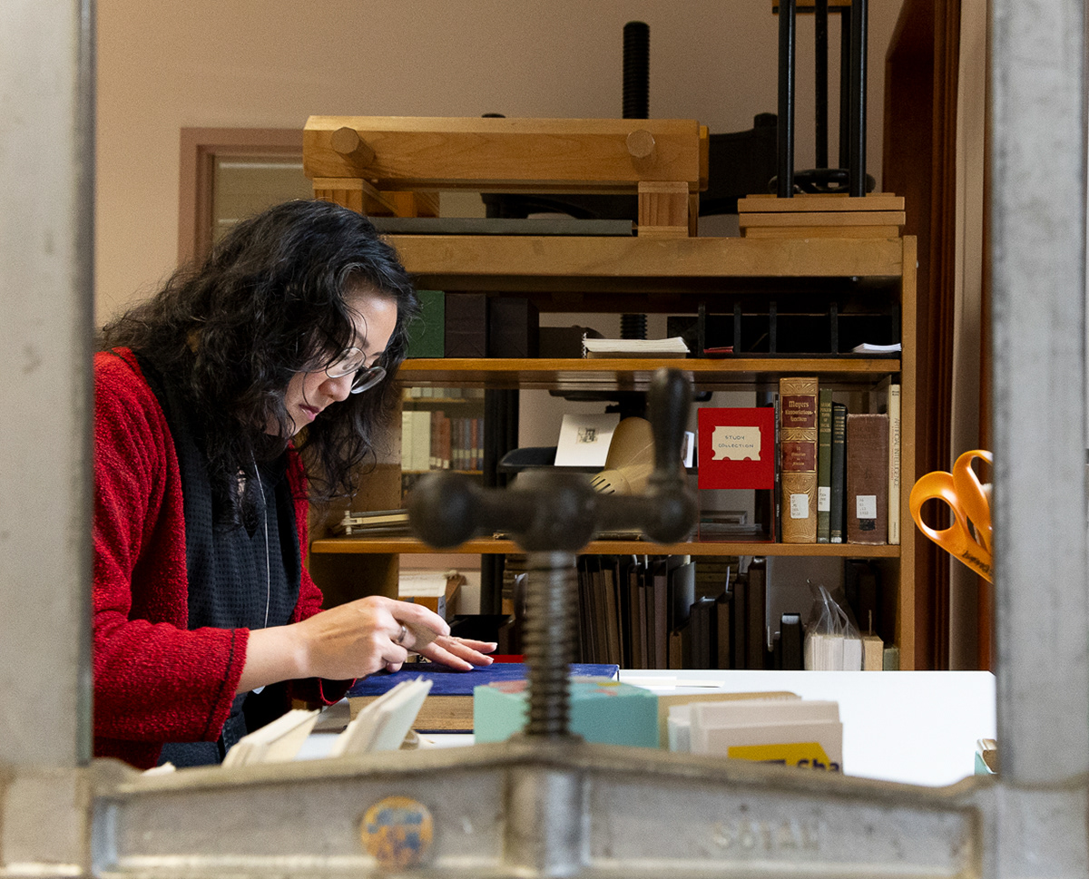 Victoria Wong, lead conservator at the Knight Library, cleans the cover of a book on Oct. 30, 2024. | Shot for Emerald Media Group | 1/125 f/5.6 ISO3200