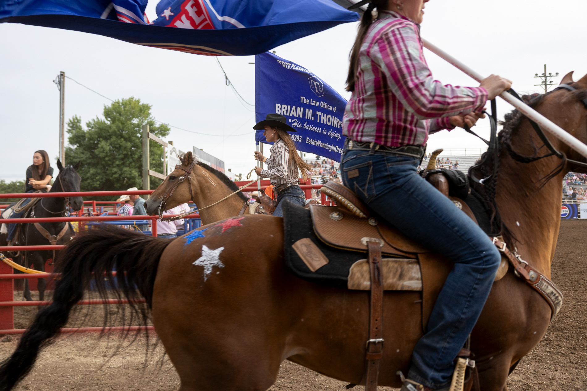 Riders with sponsor flags enter the arena at the Eugene Pro Rodeo on July 3, 2025. The night's theme was "Tough Enough To Wear Pink," a campaign promoting breast cancer awareness. | Shot for Emerald Media Group | 1/1000 f/4 ISO800