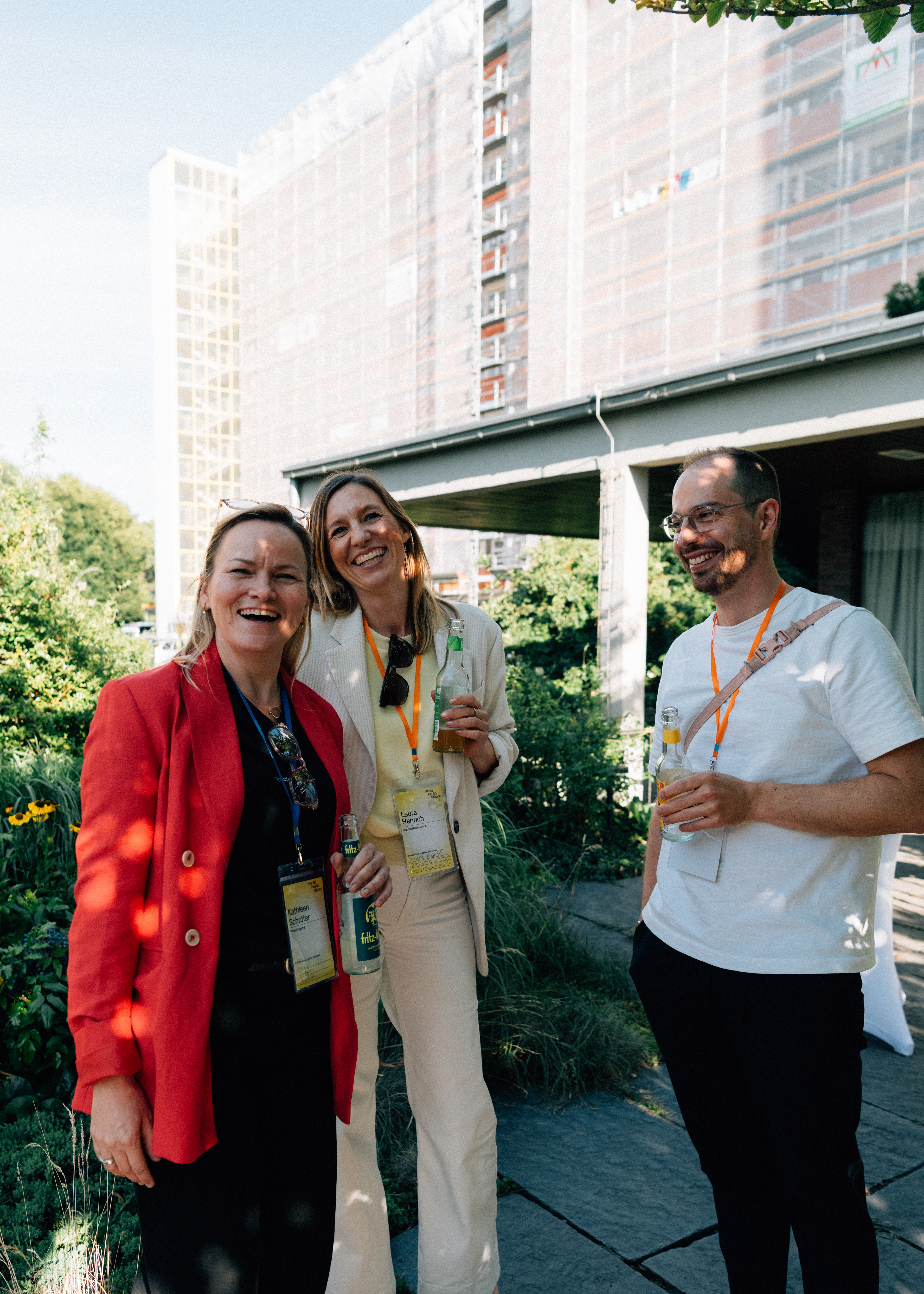 Drei Teilnehmerinnen im Gespräch bei Getränken während des Sommerfests der Mental Health Alliance.