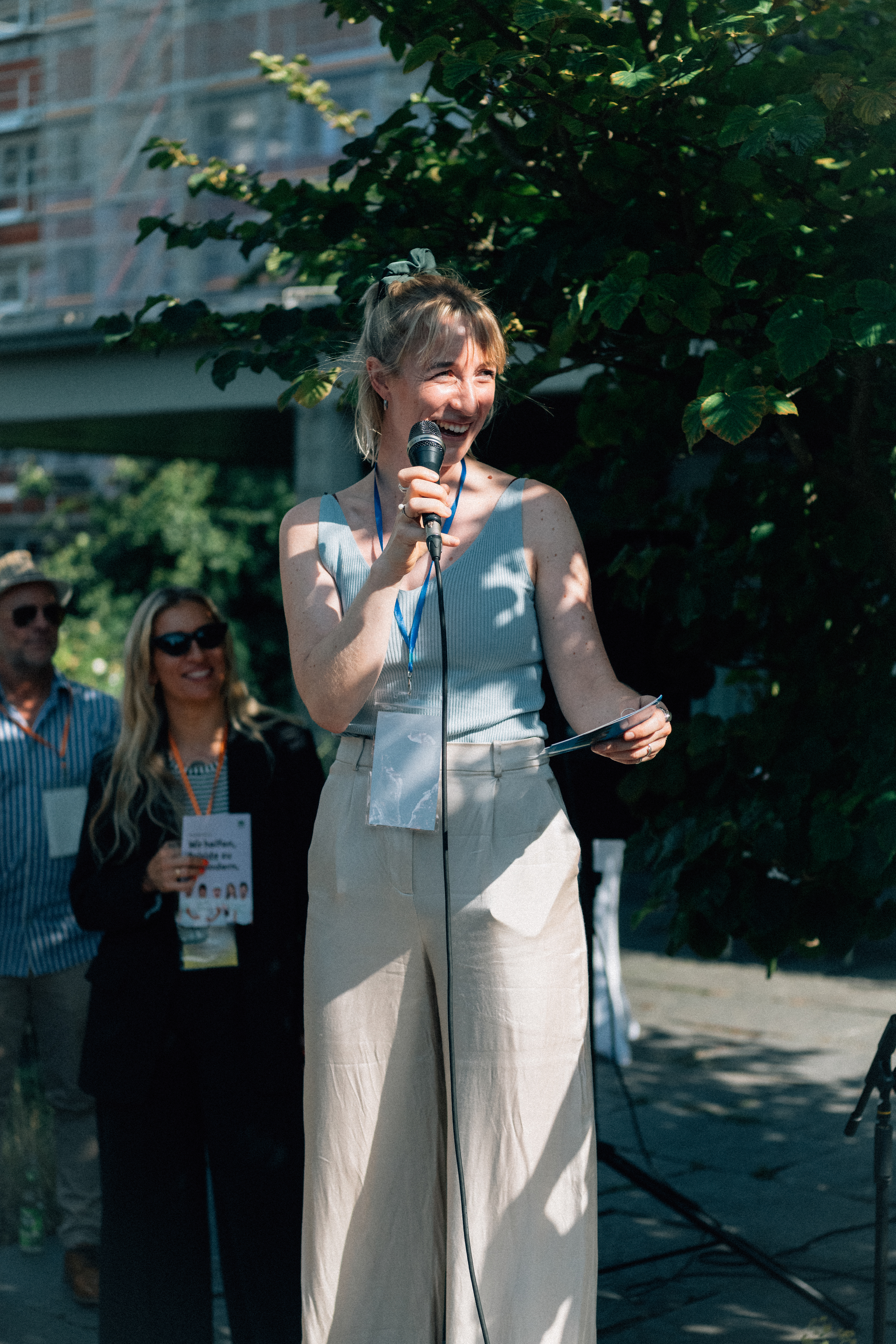 Speakerin mit Mikrofon beim Sommerfest der Mental Health Alliance in der Hansabibliothek in Berlin.