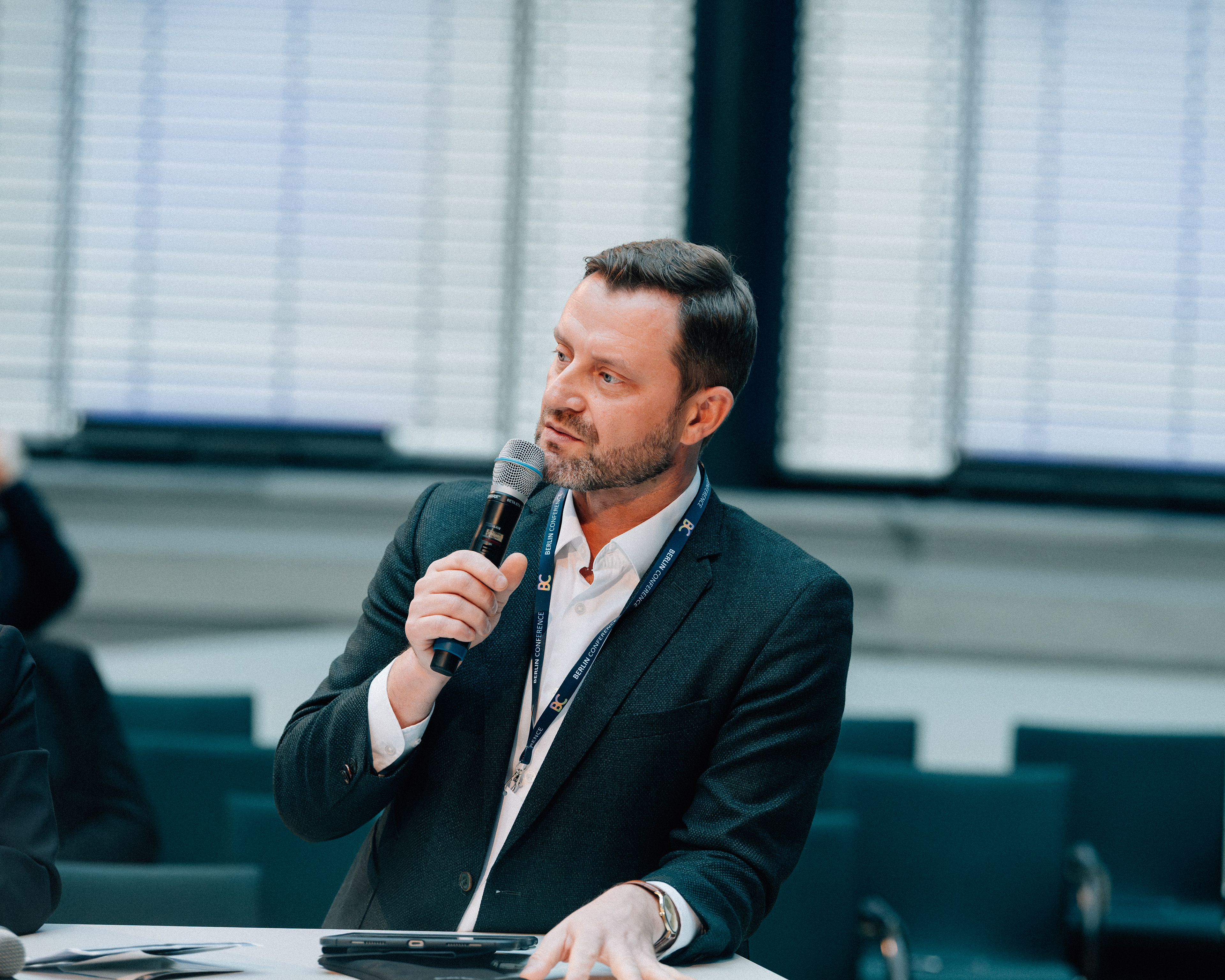 Speaker mit Mikrofon während einer Gesprächsrunde bei der Berlin Conference.