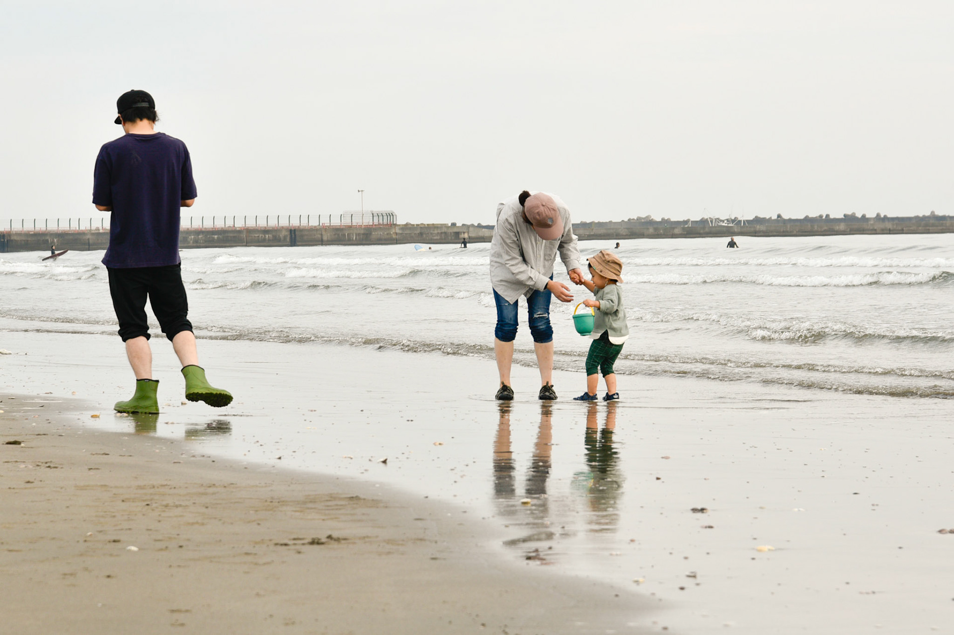 Le père la mère et leur fils sur la plage au bord de l'eau au Japon avec en arrière fond un ciel gris
