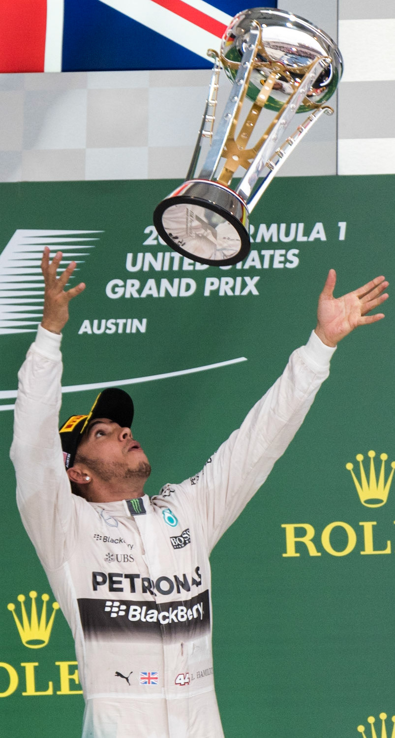 Lewis Hamilton of Mercedes AMG Petronas, throws the race trophy into the air in podium celebration after winning both the US Grand Prix and the 2015 Formula 1 Drivers' Championship.