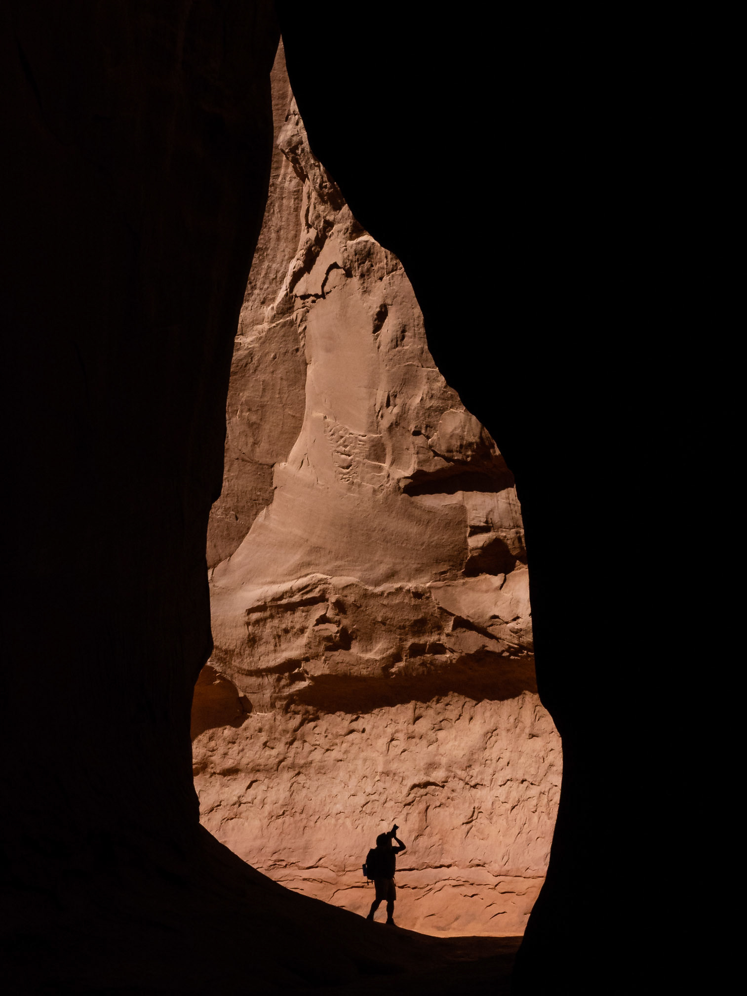 A photographer seen silhouetted against a wall inside Leprechaun Canyon near Hanksville, Utah.