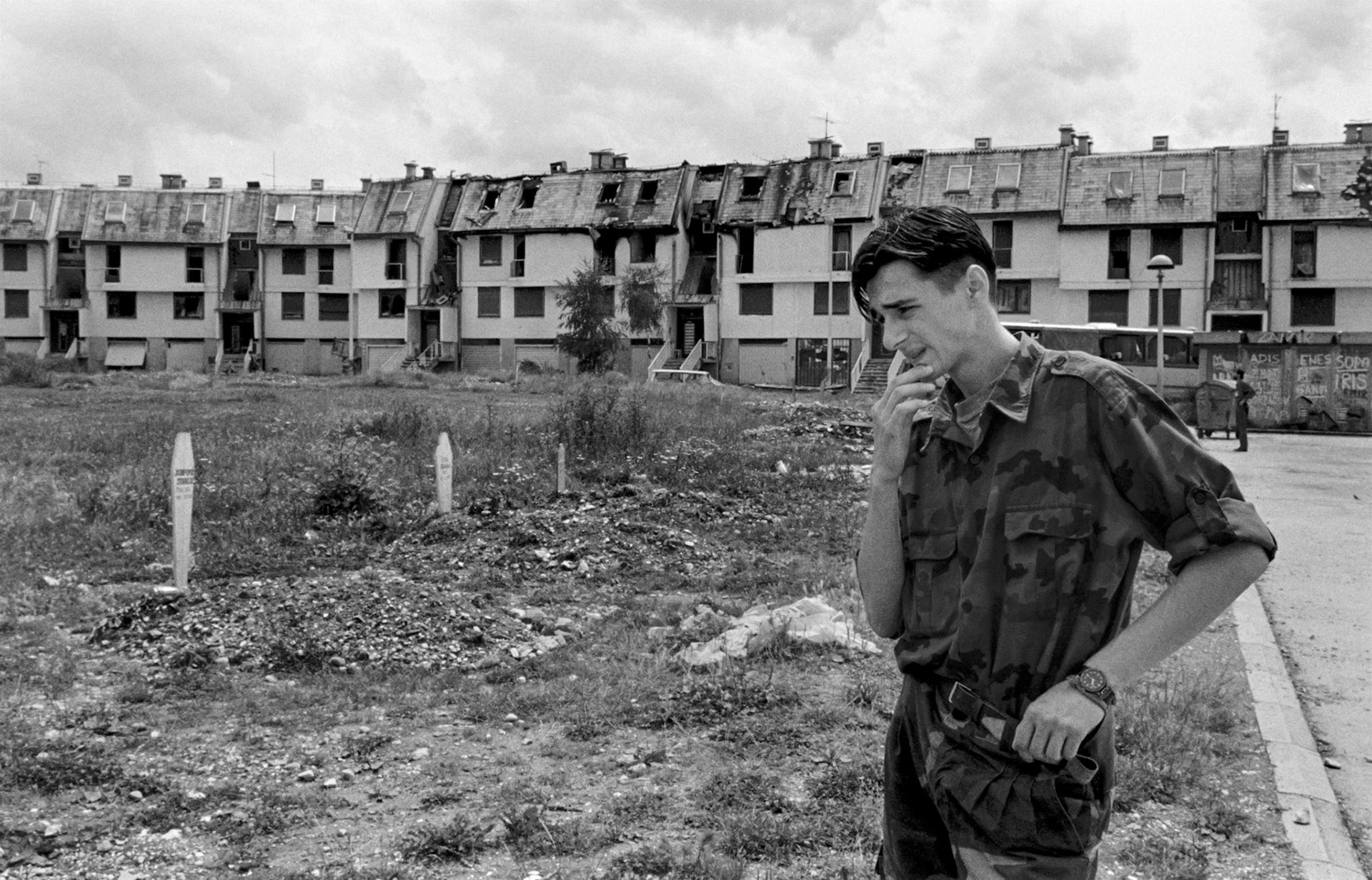 A young Bosnian government fighter pauses at a makeshift graveyard in Sarajevo on June 30, 1992. Several of his comrades are buried here.