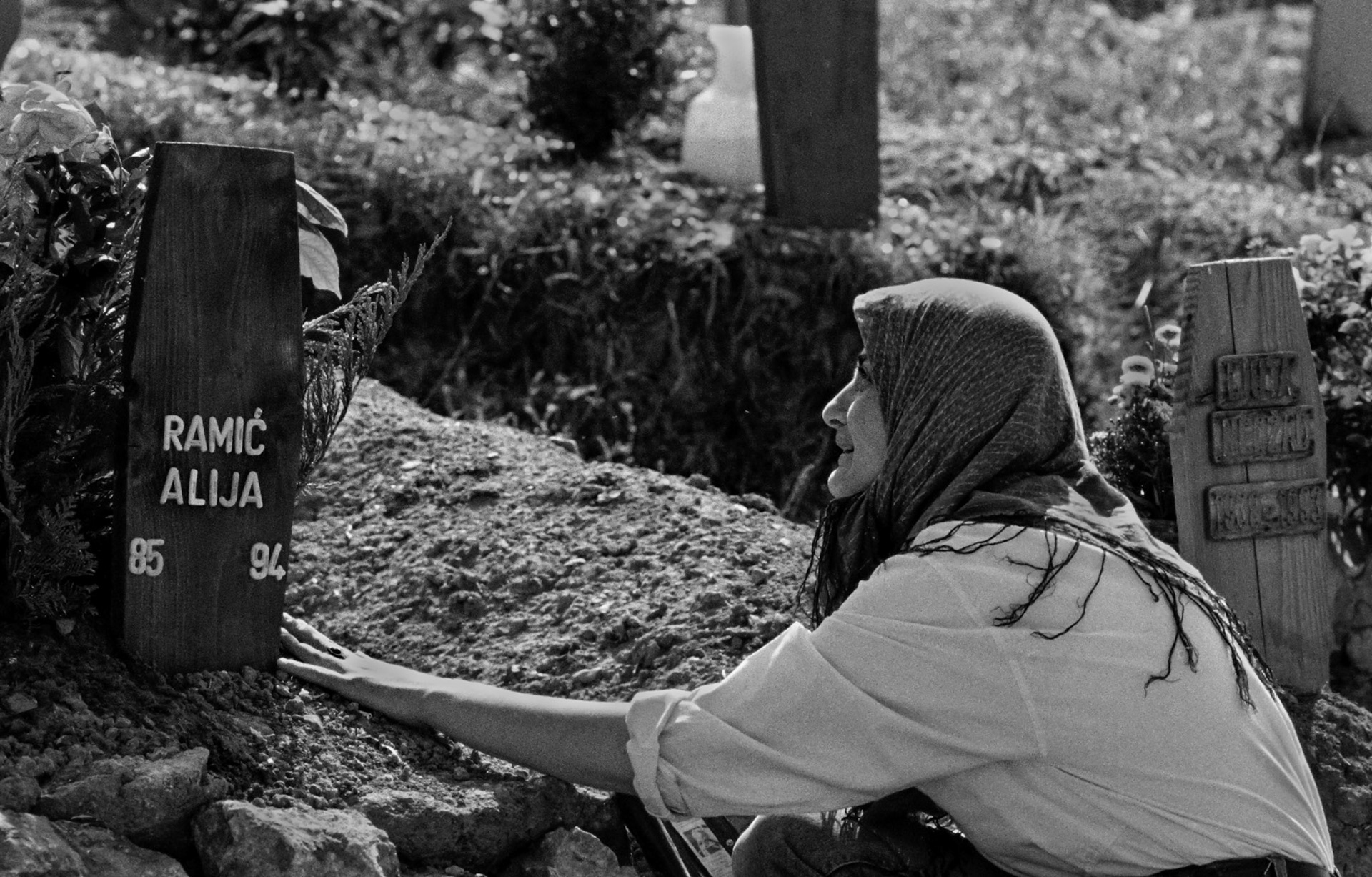 A Bosnian woman cries as she touches her son's grave in Sarajevo's Lion's cemetery on August 23, 1994.