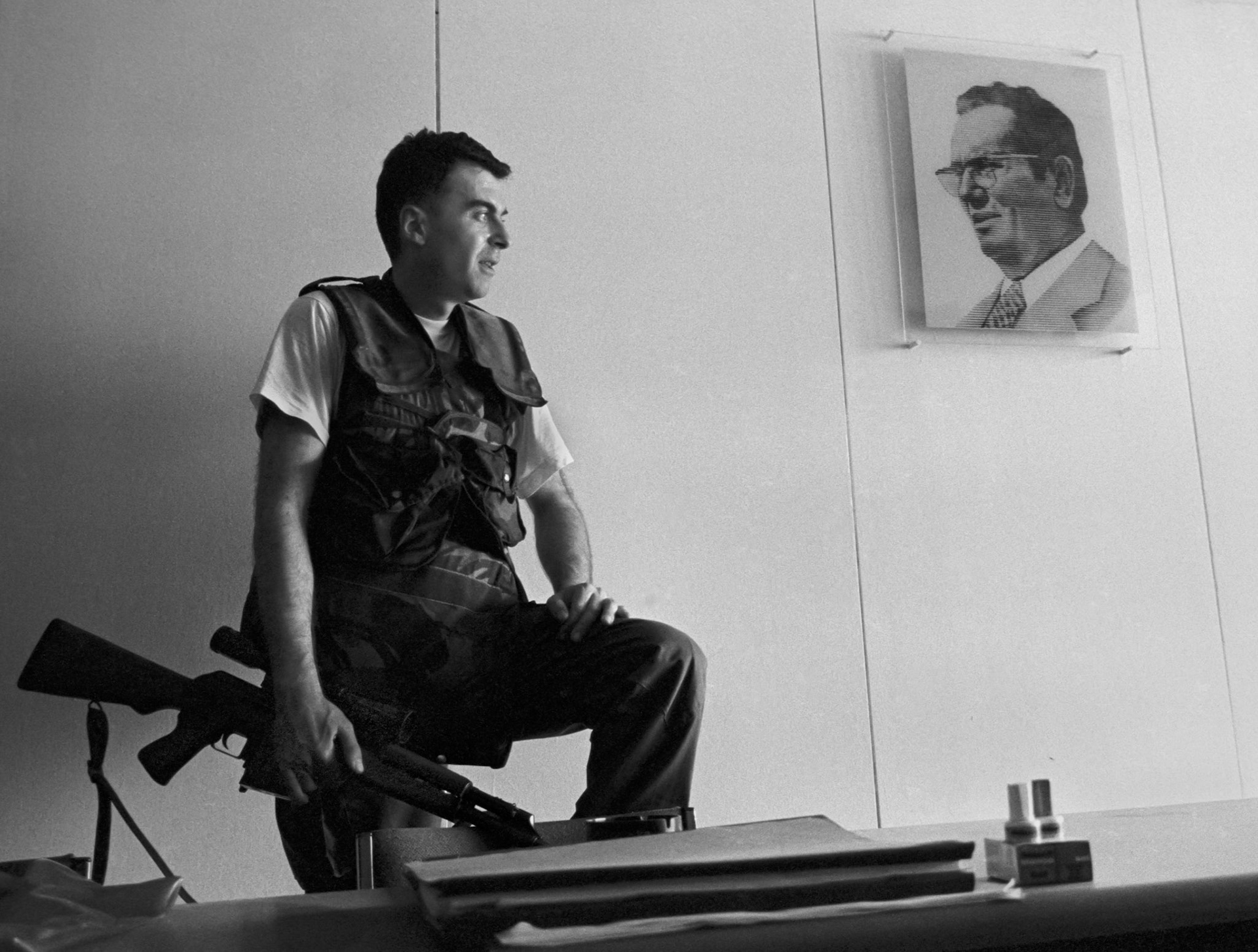 A Bosnian Army sniper armed with a Dragunov rifle looks past a portrait of the late Yugoslav leader Joseph Tito in his position in a Sarajevo office building on June 19, 1992.