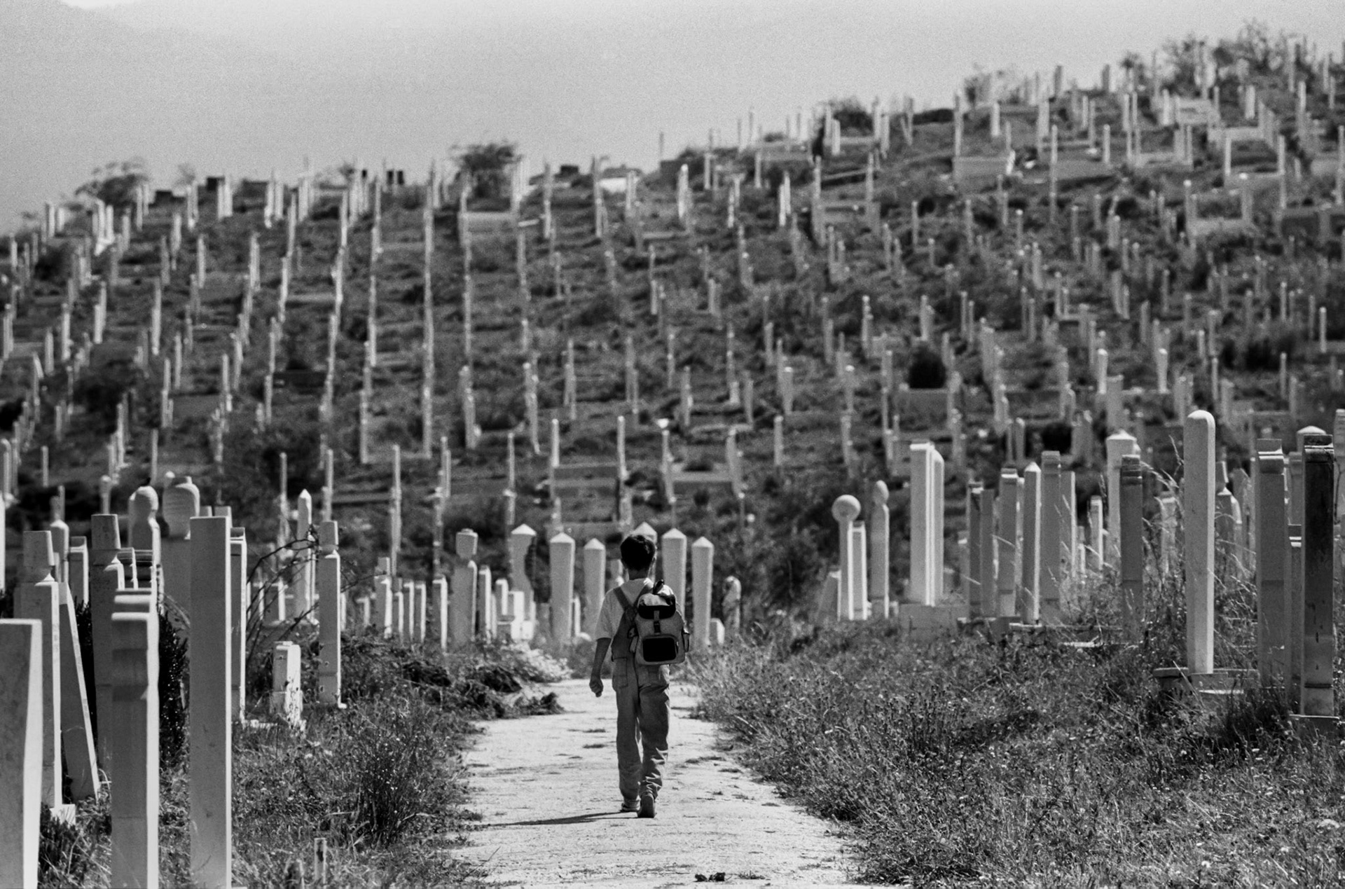 A boy walks through a cemetery on his way to school in the besieged Bosnian capital Sarajevo on September 10, 1994.