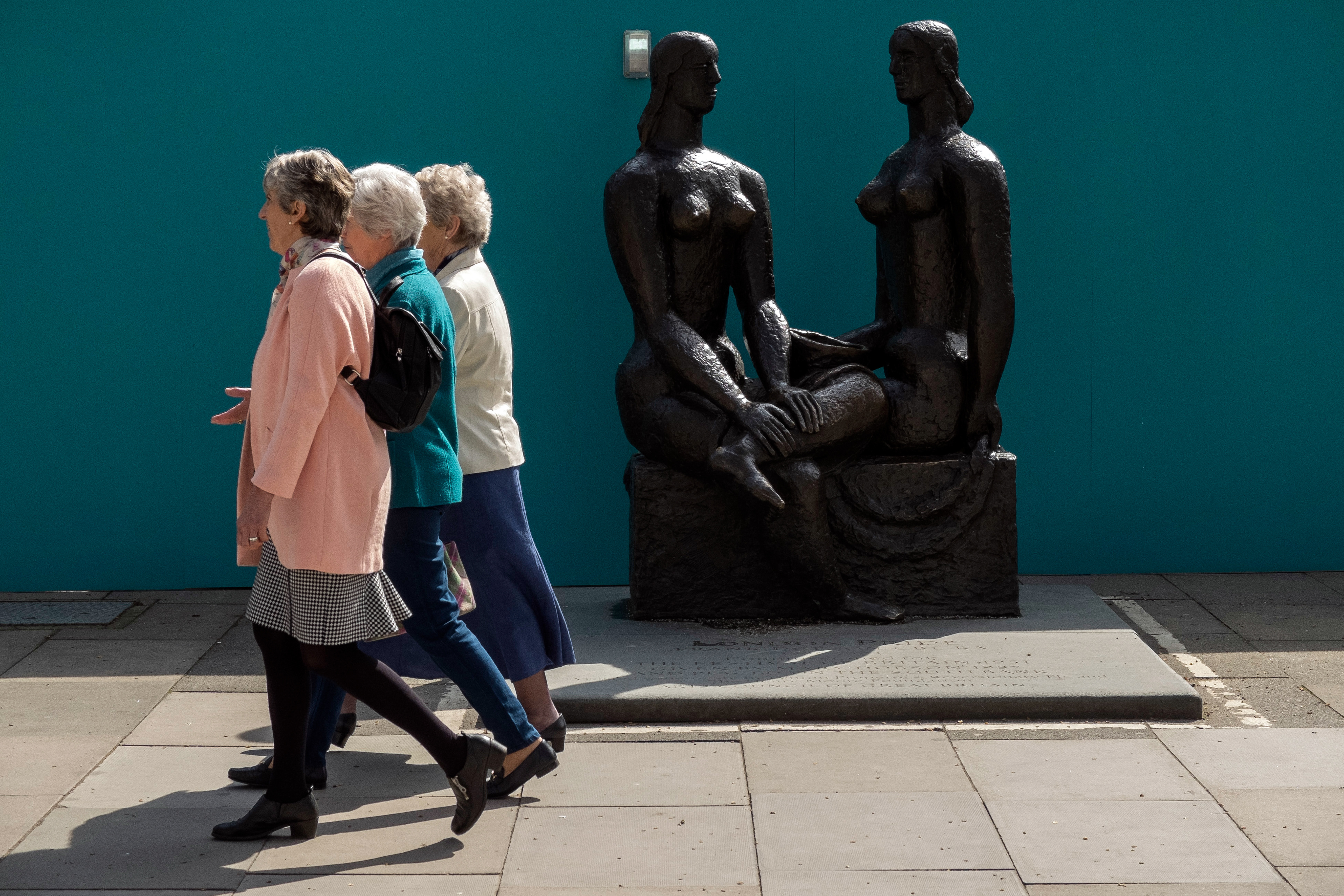 Pedestrians walk past bronze sculpture on the Southbank in London