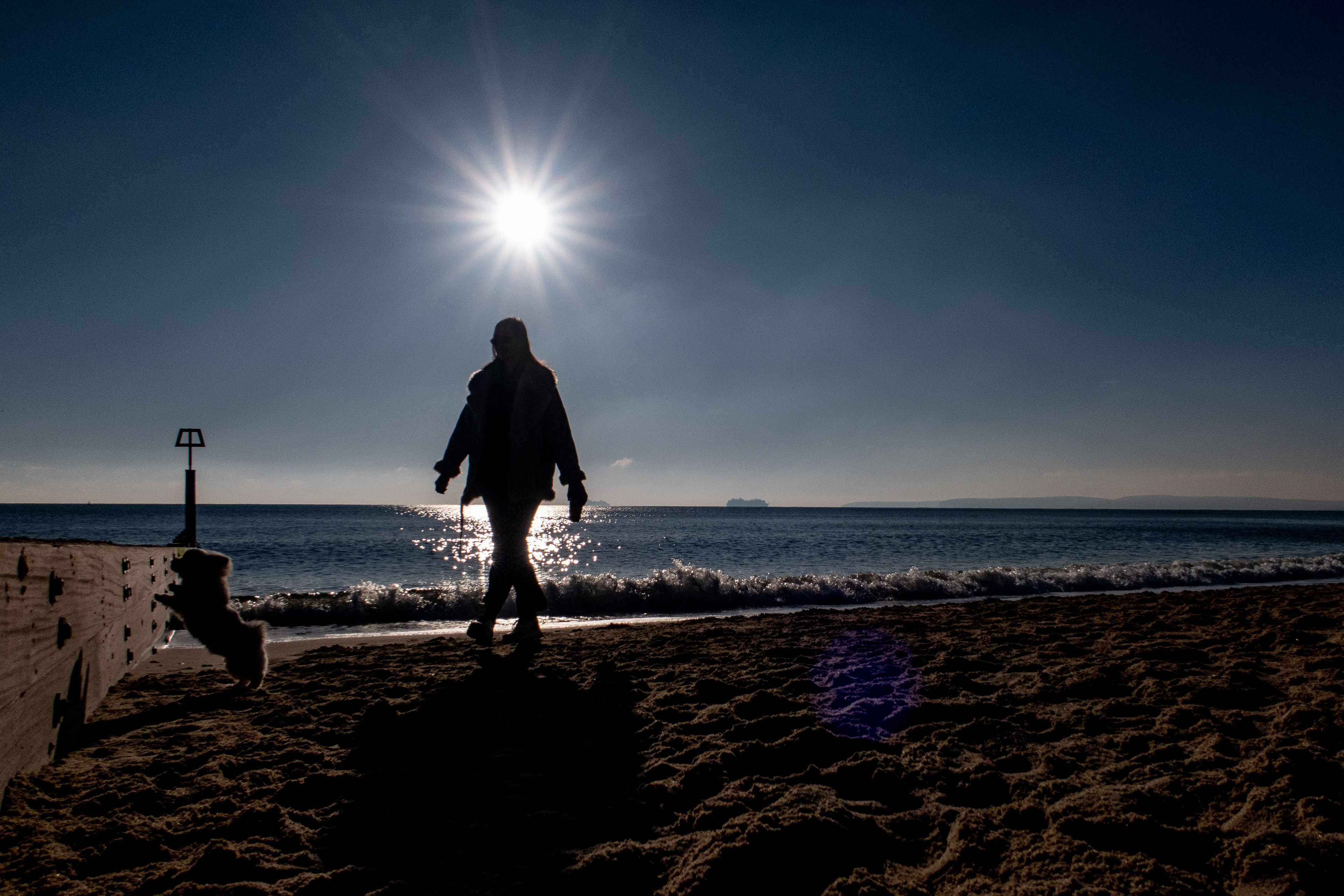 Dog walker on the beach at Boscombe in Dorset