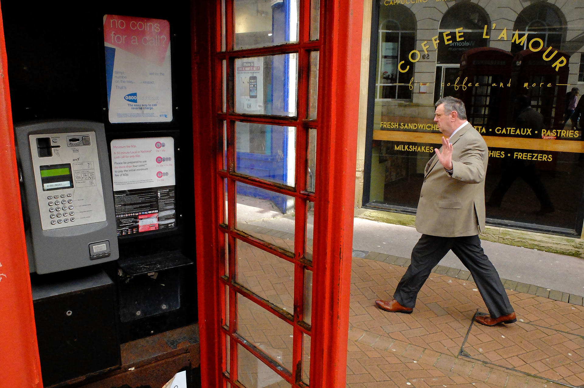 Man gestures 'no pictures' as he walks past a vandalised phone box in Bournemouth