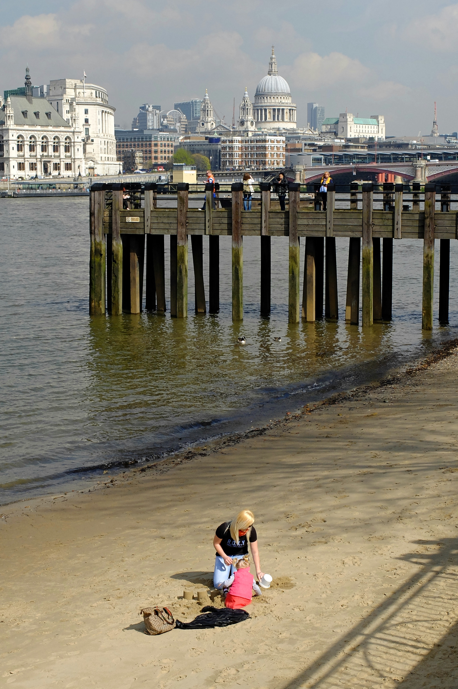 Adult and child play on one of the River Thames beaches that only show at low tide, London