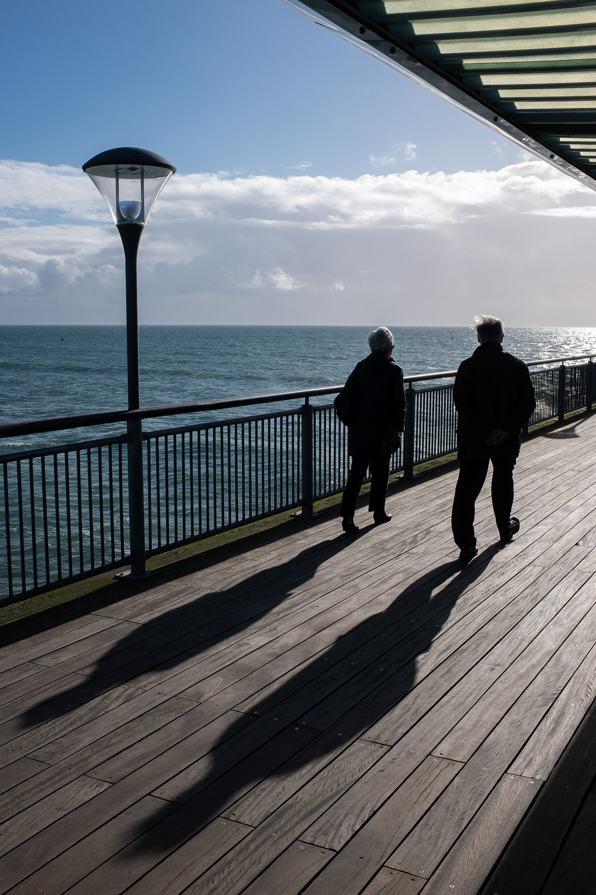 Couple walk along the pier at Boscombe, Dorset