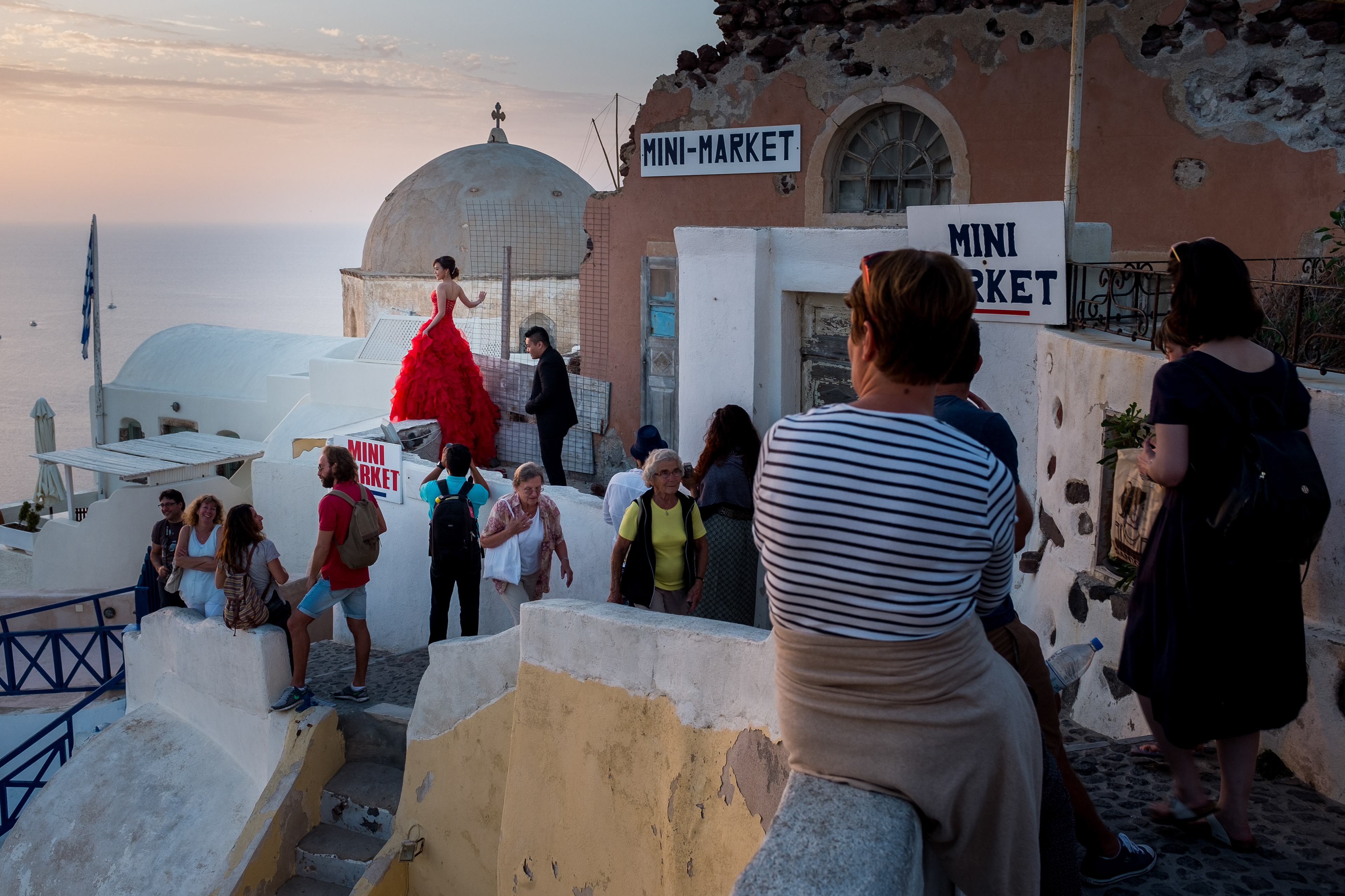 A bride poses for photographs amongst the tourists waiting for the sunset on Santorini