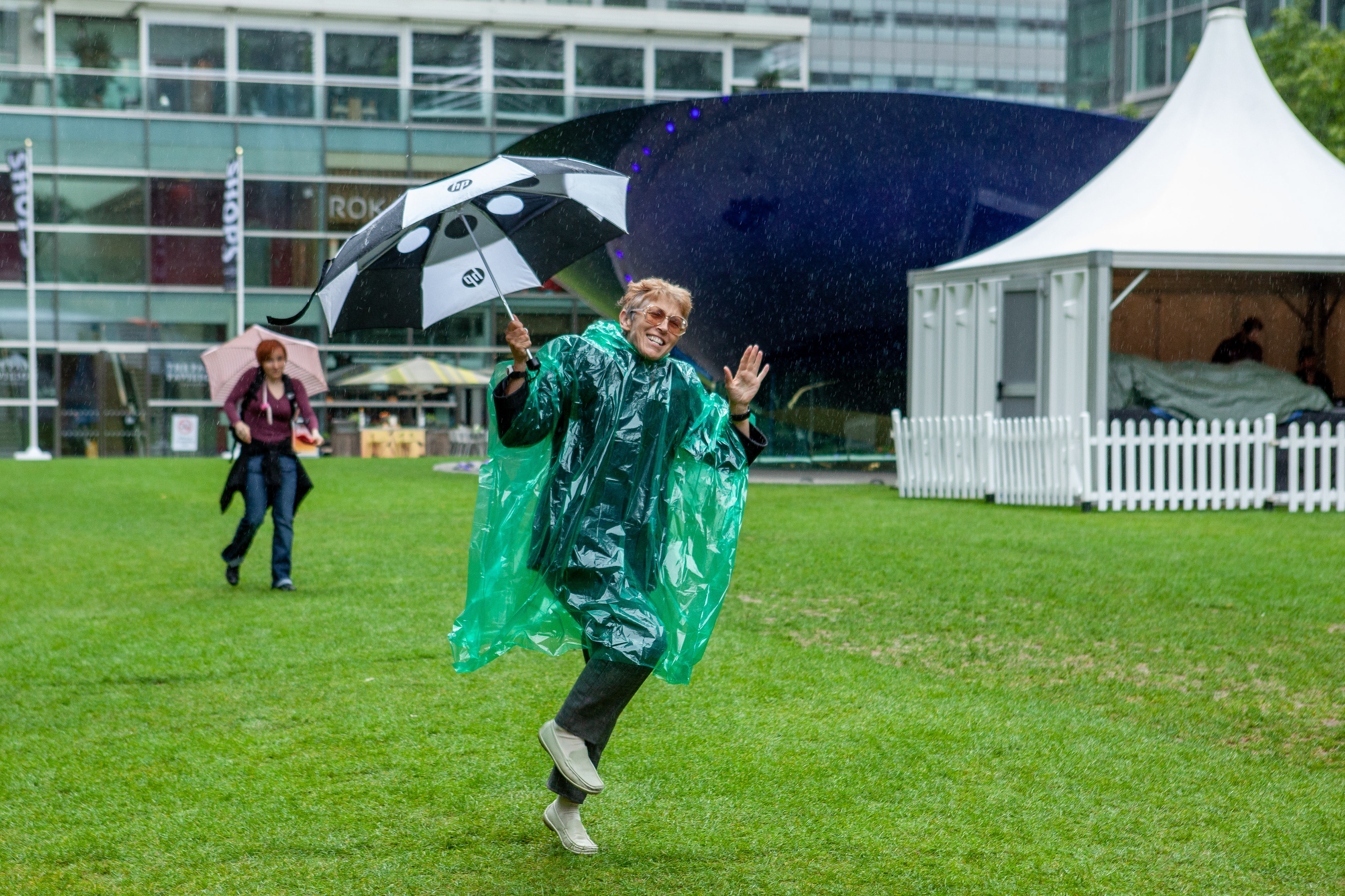 Audience member dances in the pouring rain at an arts festival at Canary Wharf, London