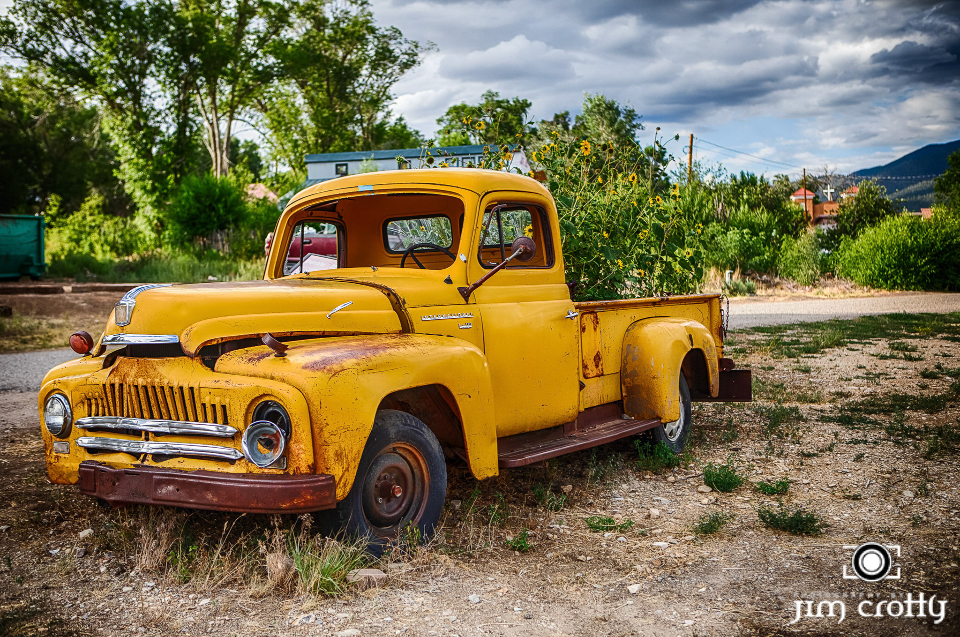 Old cars and landscape in Questa, New Mexico by Jim Crotty