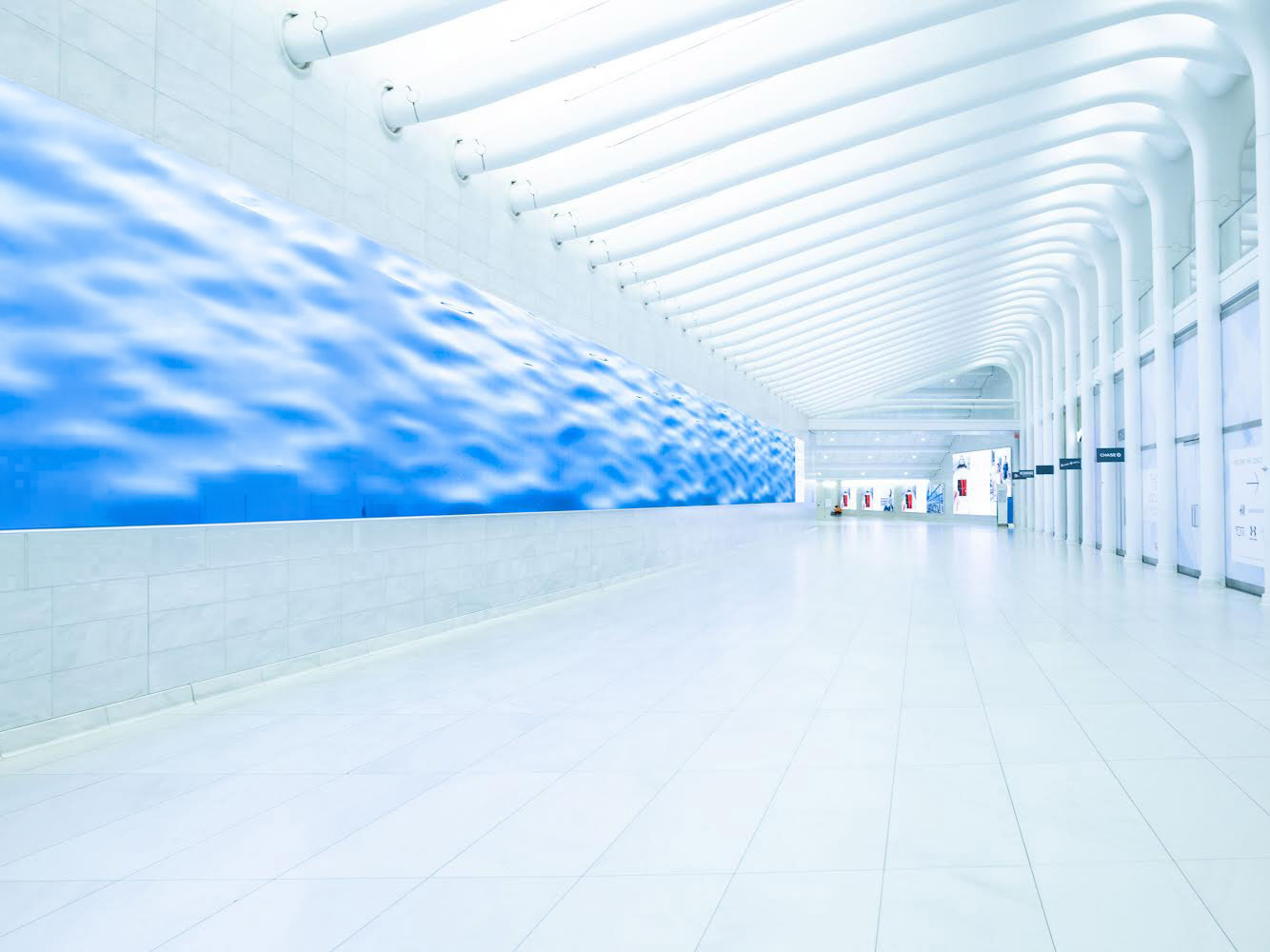 Empty Oculus hallway in NYC connecting to PATH train with long white architectural corridor