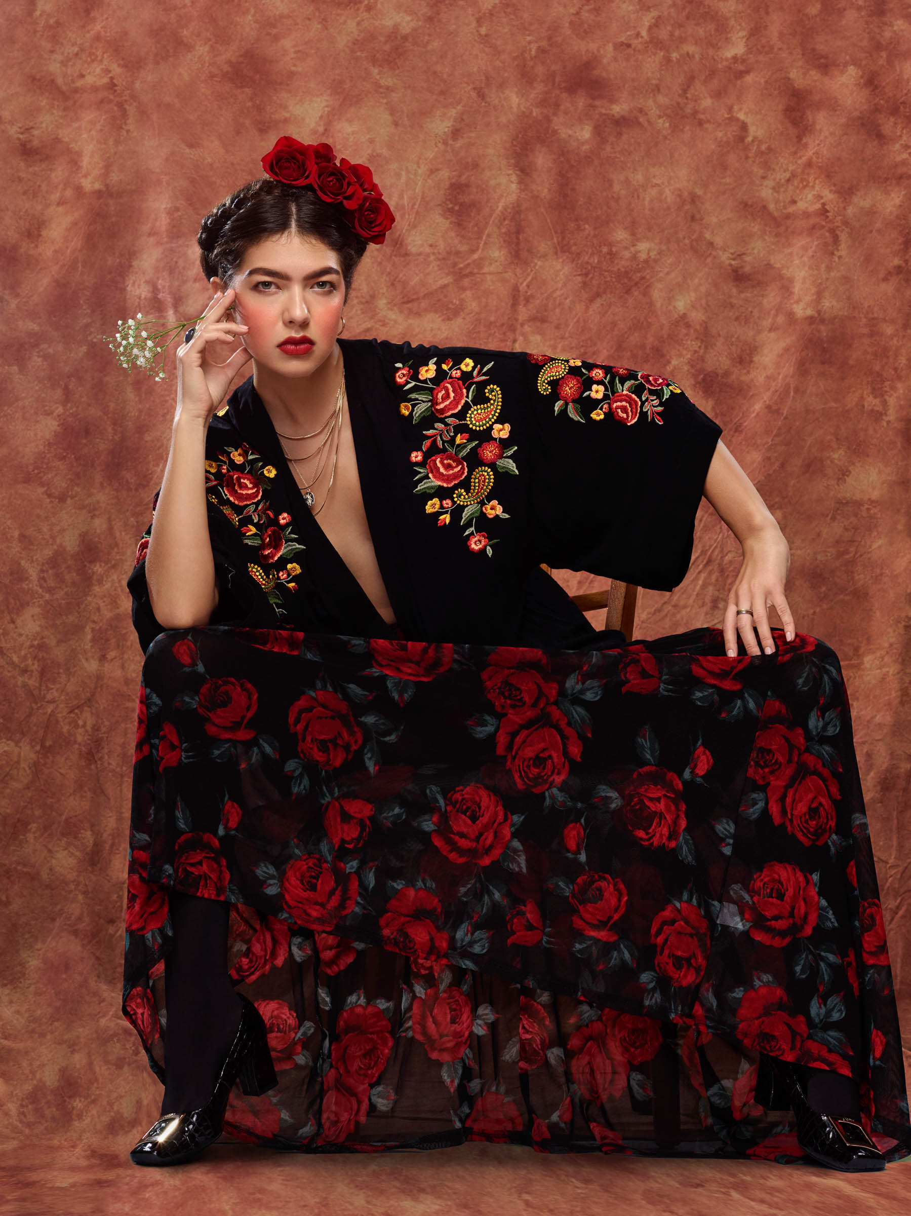 Frida Kahlo inspired seated portrait with woman in floral dress facing camera