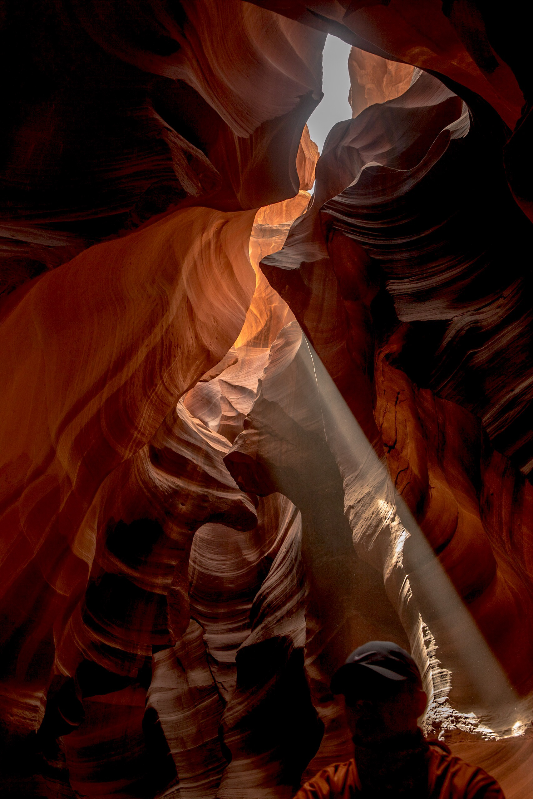 Light beam in Antelope Canyon with silhouetted guide standing in shadow