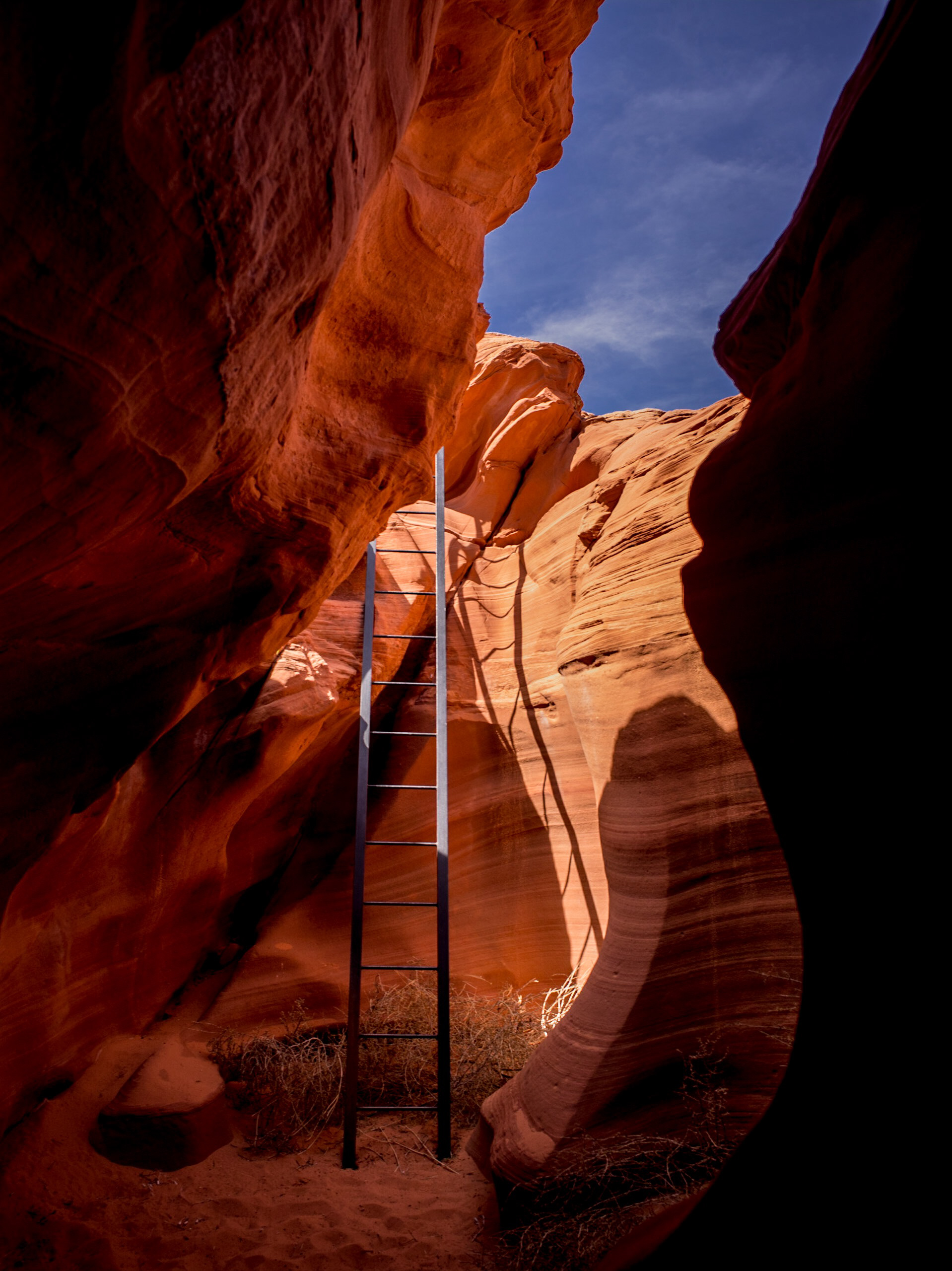 Ladder leading out of a narrow sandstone crevice inside Antelope Canyon in Arizona, photographed by Ken Jones.