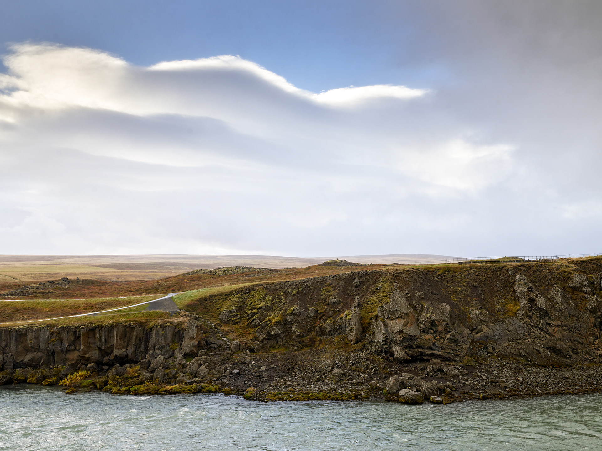 Iceland cliffside landscape with water below and dramatic cloud formations above