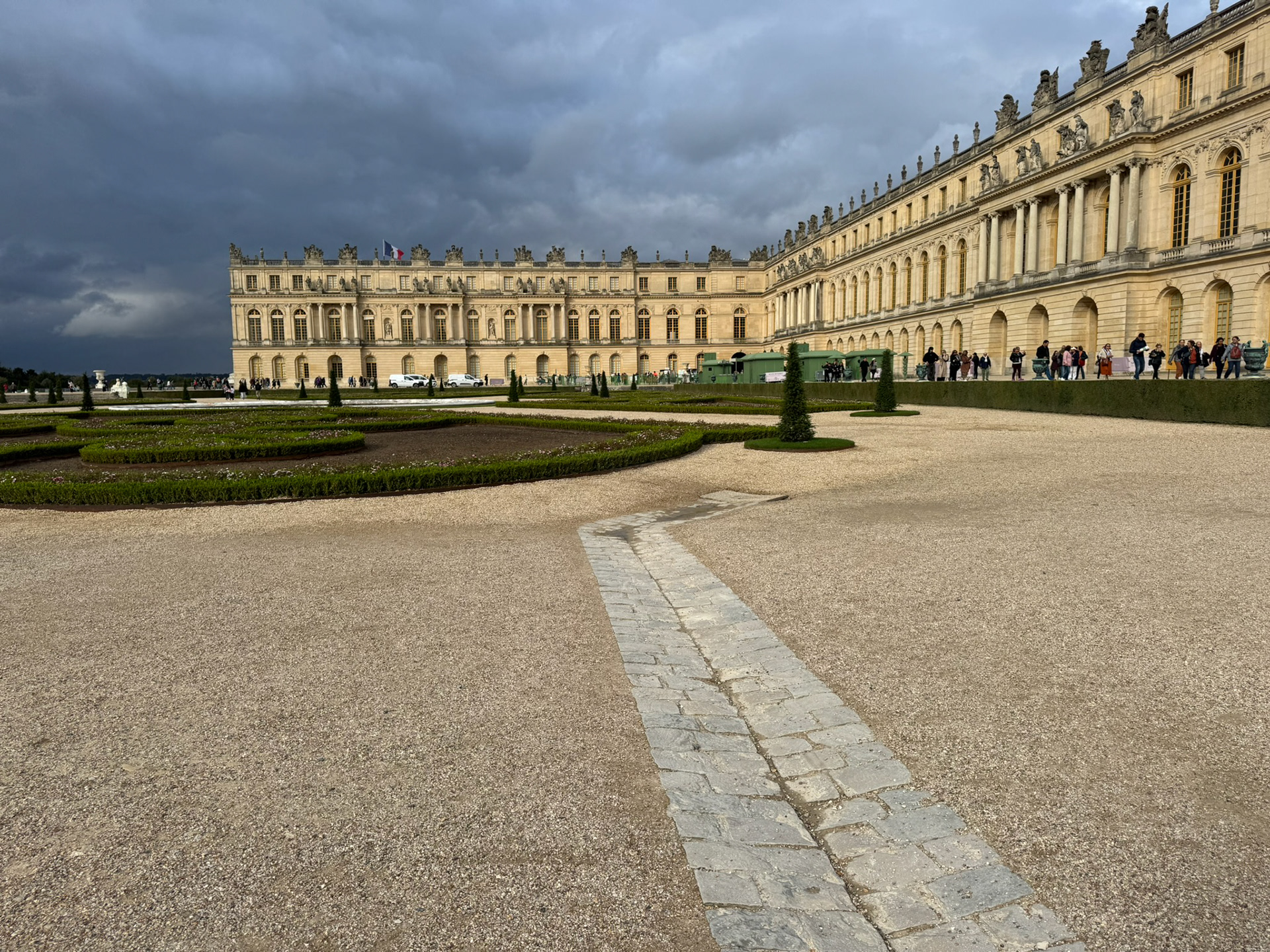 Versailles courtyard with visitors near entrance and circular hedge in center