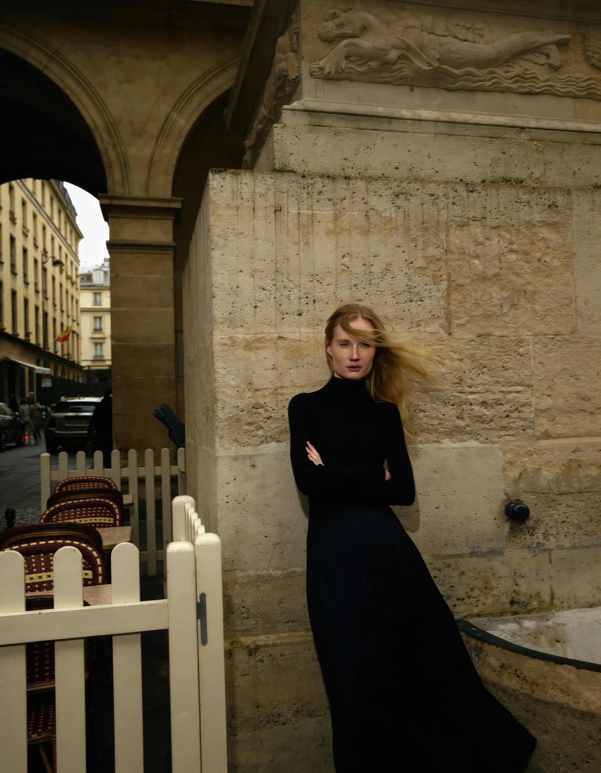 Paris fashion editorial model in black dress with windblown hair against historic architecture