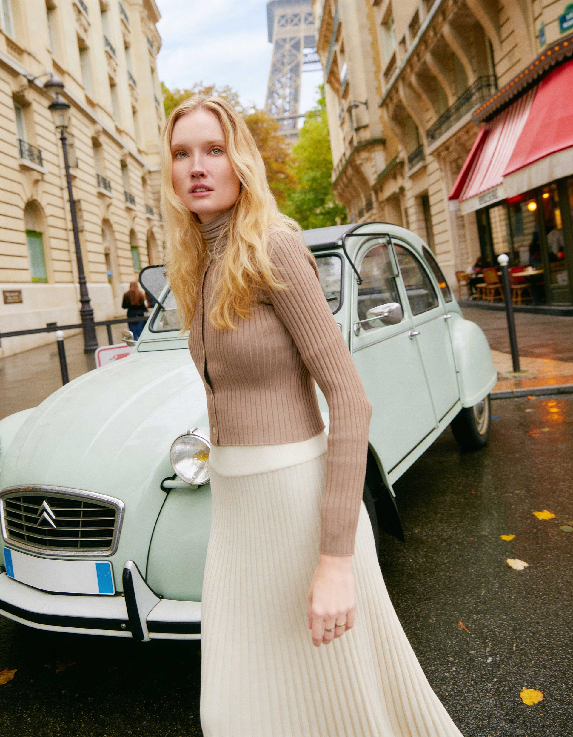 Model walking past vintage Citroen car with Eiffel Tower in Paris wearing modest fall fashion editorial look
