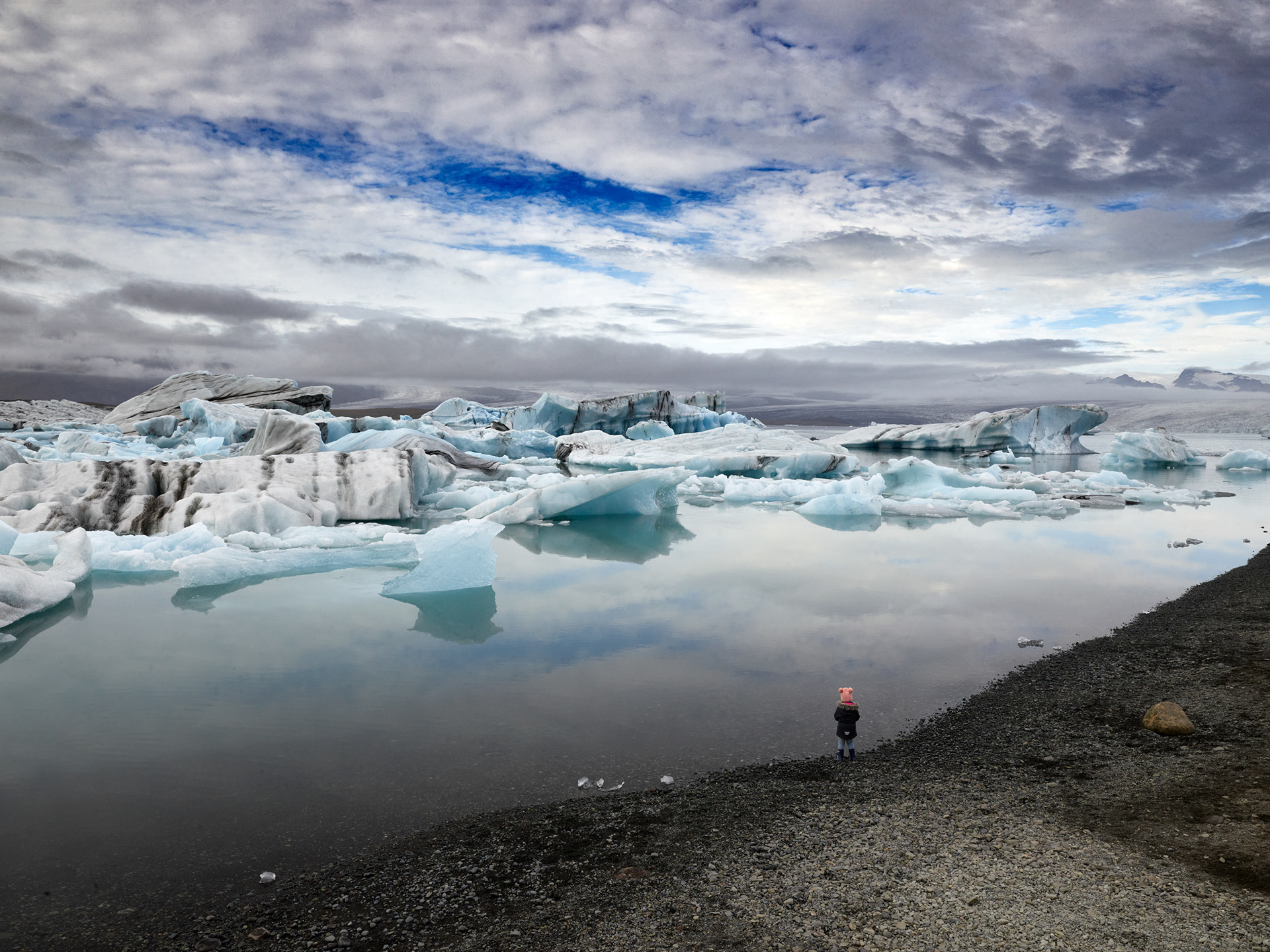 Young girl standing on Diamond Beach in Iceland looking at icebergs on black sand beach