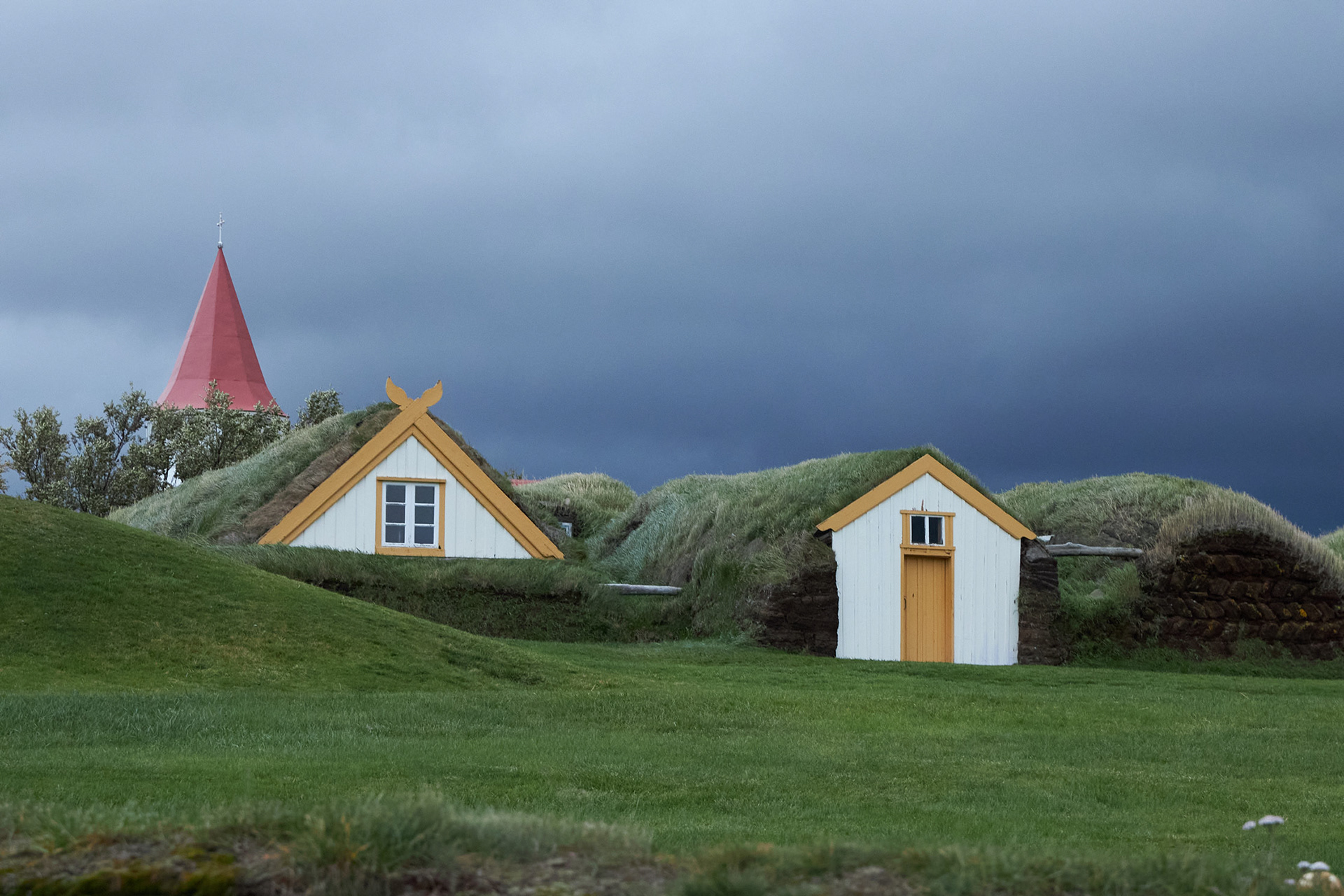 Glaumbær turf houses in Skagafjordur Iceland with grass roofs and dramatic sky, traditional Icelandic architecture in rural northern landscape