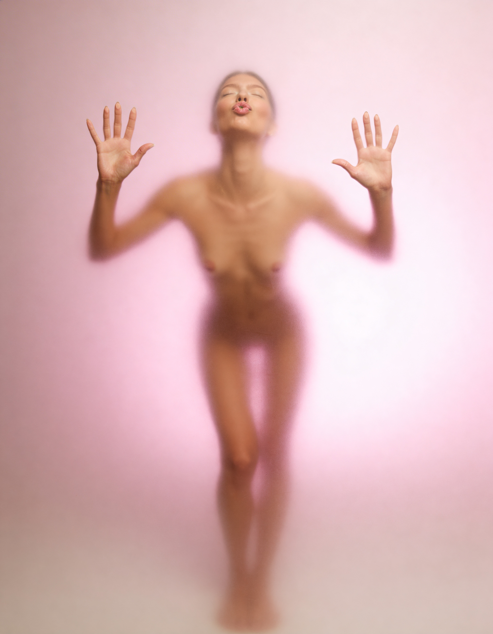 Female figure pressed against frosted glass creating silhouette of body shape and form