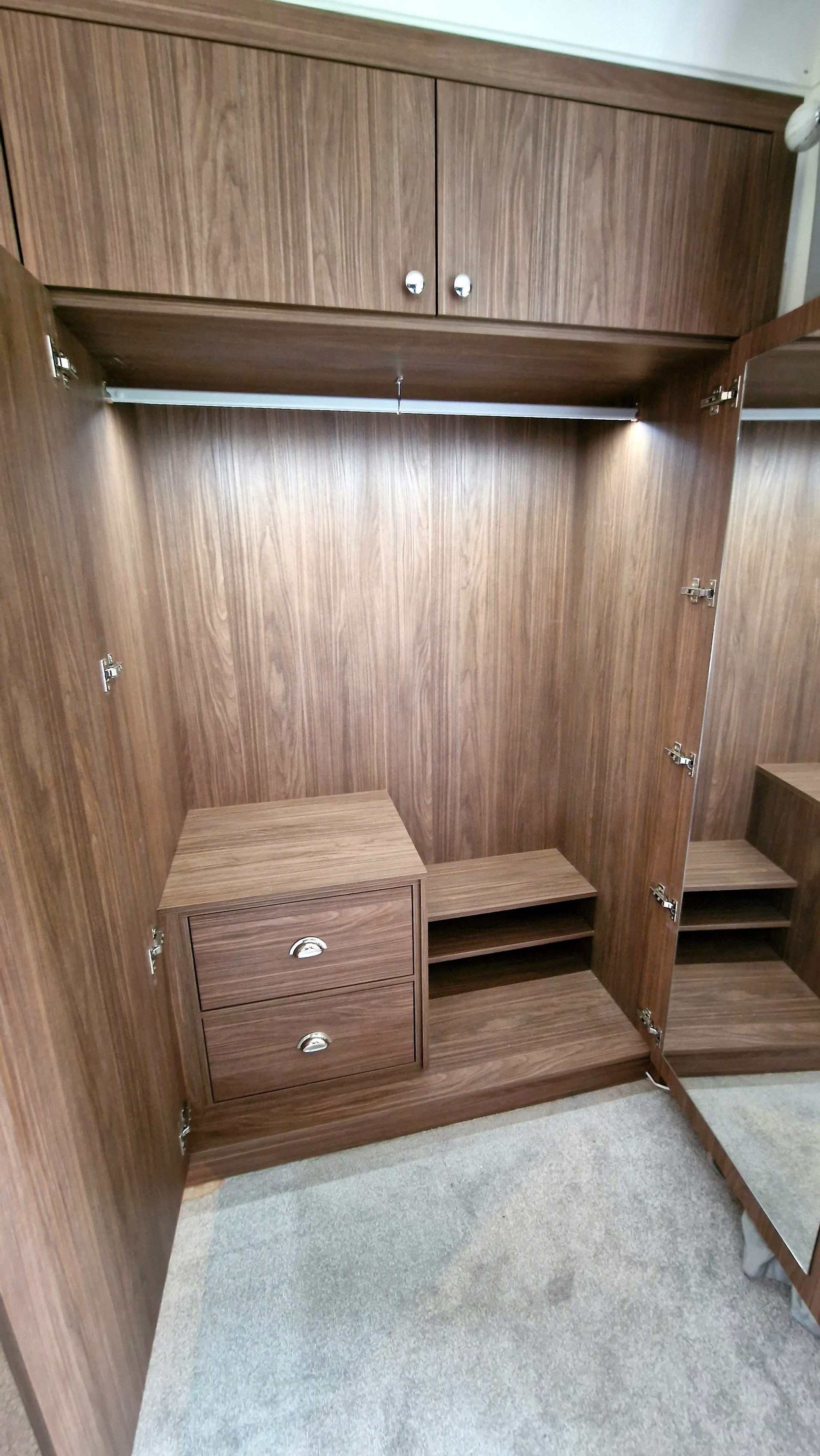 Master bedroom custom fitted wardrobes in Lincoln Walnut. Featuring LED rails and soft close Blum hardware.