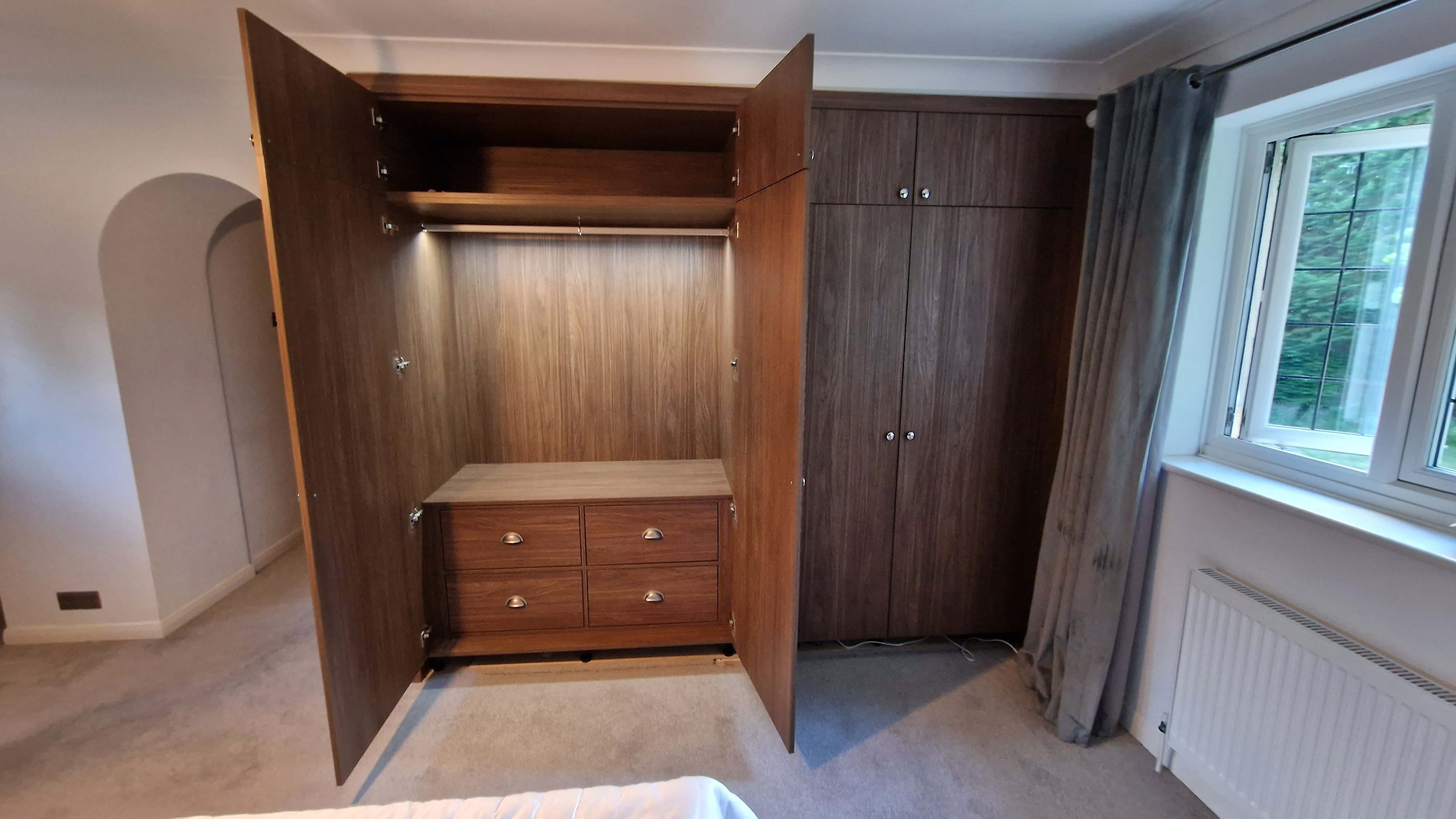 Master bedroom custom fitted wardrobes in Lincoln Walnut. Featuring LED rails and soft close Blum hardware.