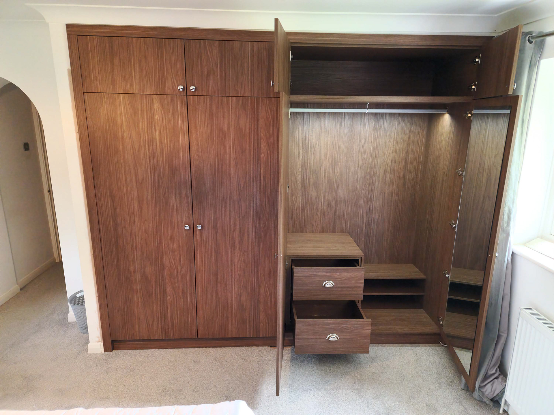 Master bedroom custom fitted wardrobes in Lincoln Walnut. Featuring LED rails and soft close Blum hardware.