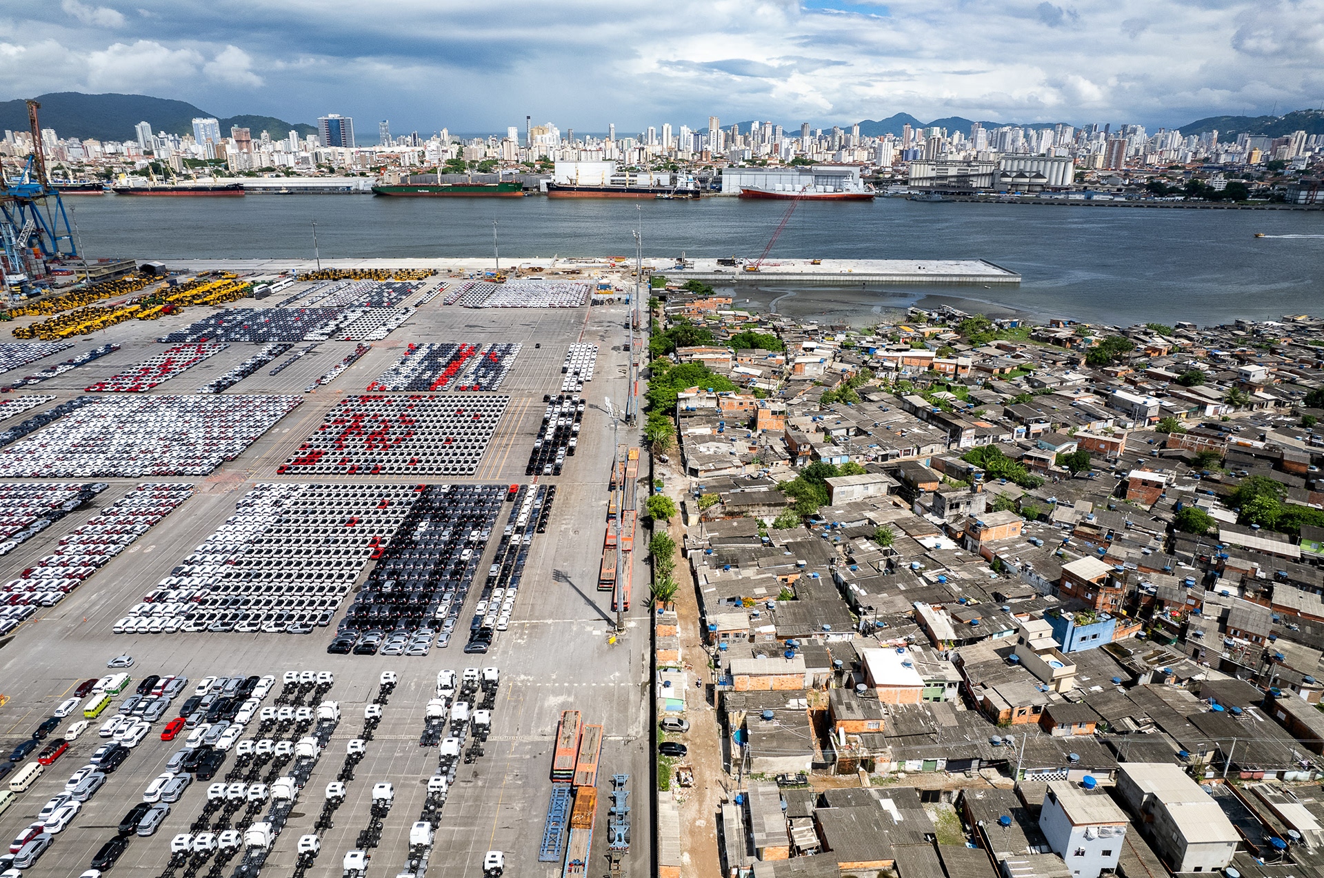 Panoramic shot of Santos port showing rows of containers and cranes, backed by the city’s skyline and hemmed by distant hills.