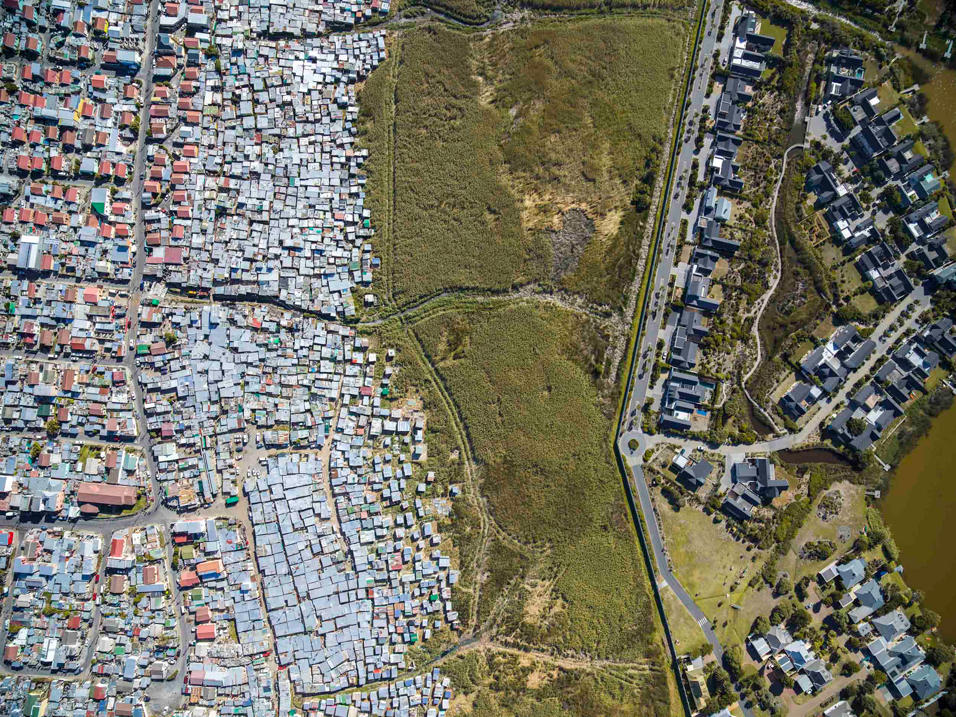 slums next to a lake with wealthy homes in cape town
