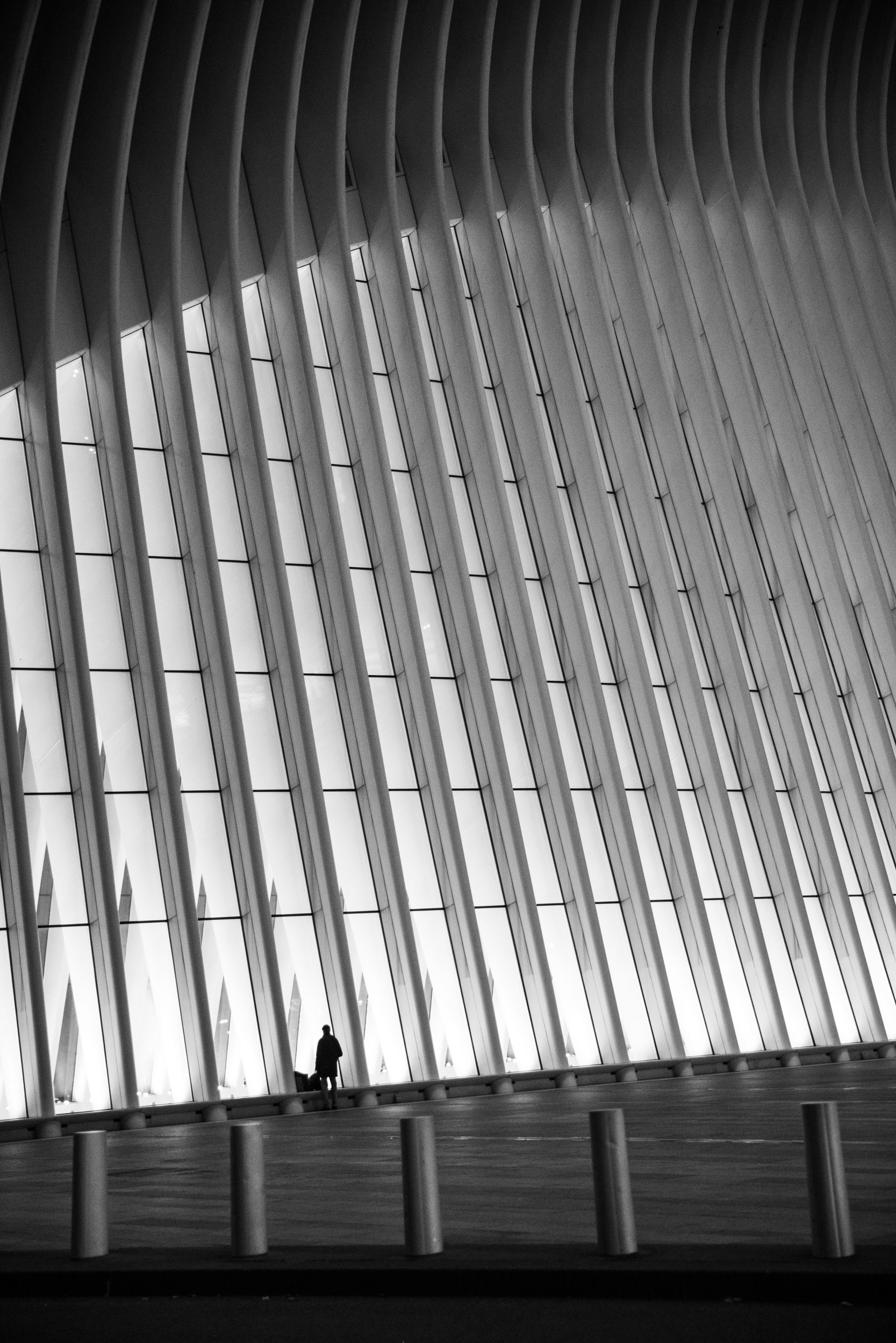 A man walking past a large architectural feature, black and white.