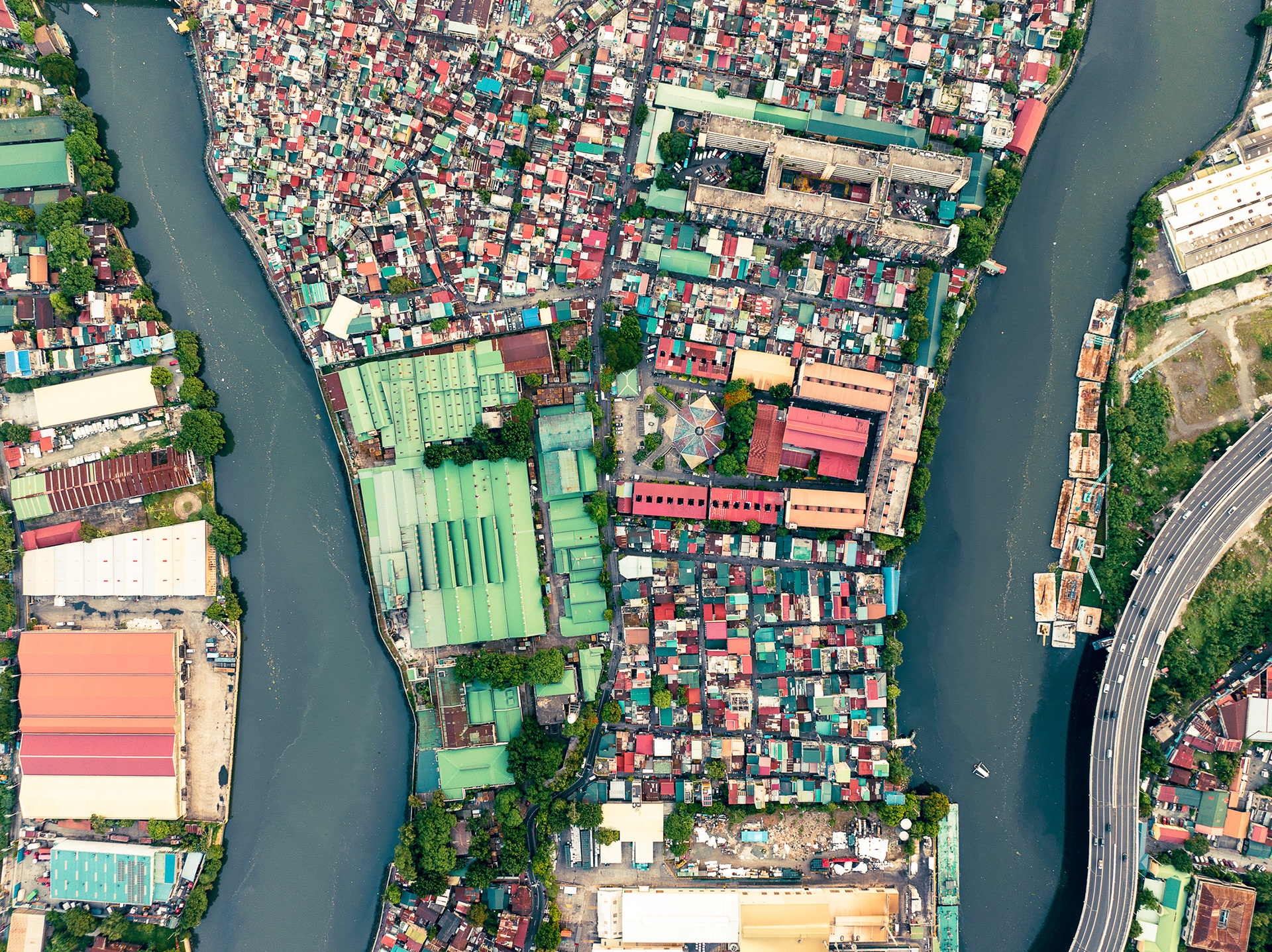 Informal homes packed near Manila port with freight trucks, illustrating pollution and spatial stress.