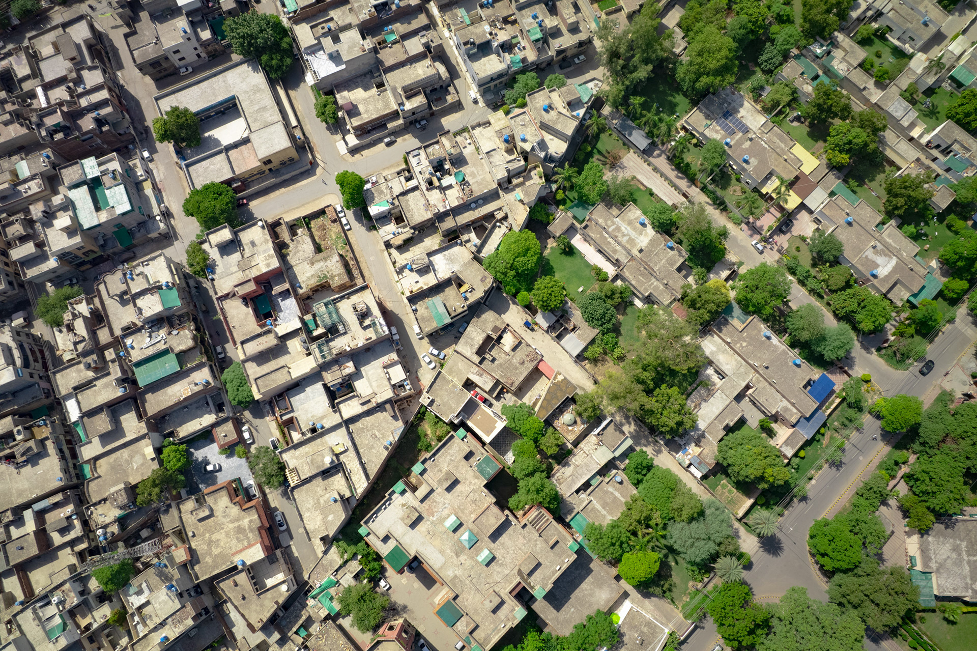 A drone view of a green neighborhood and a grey neighborhood.