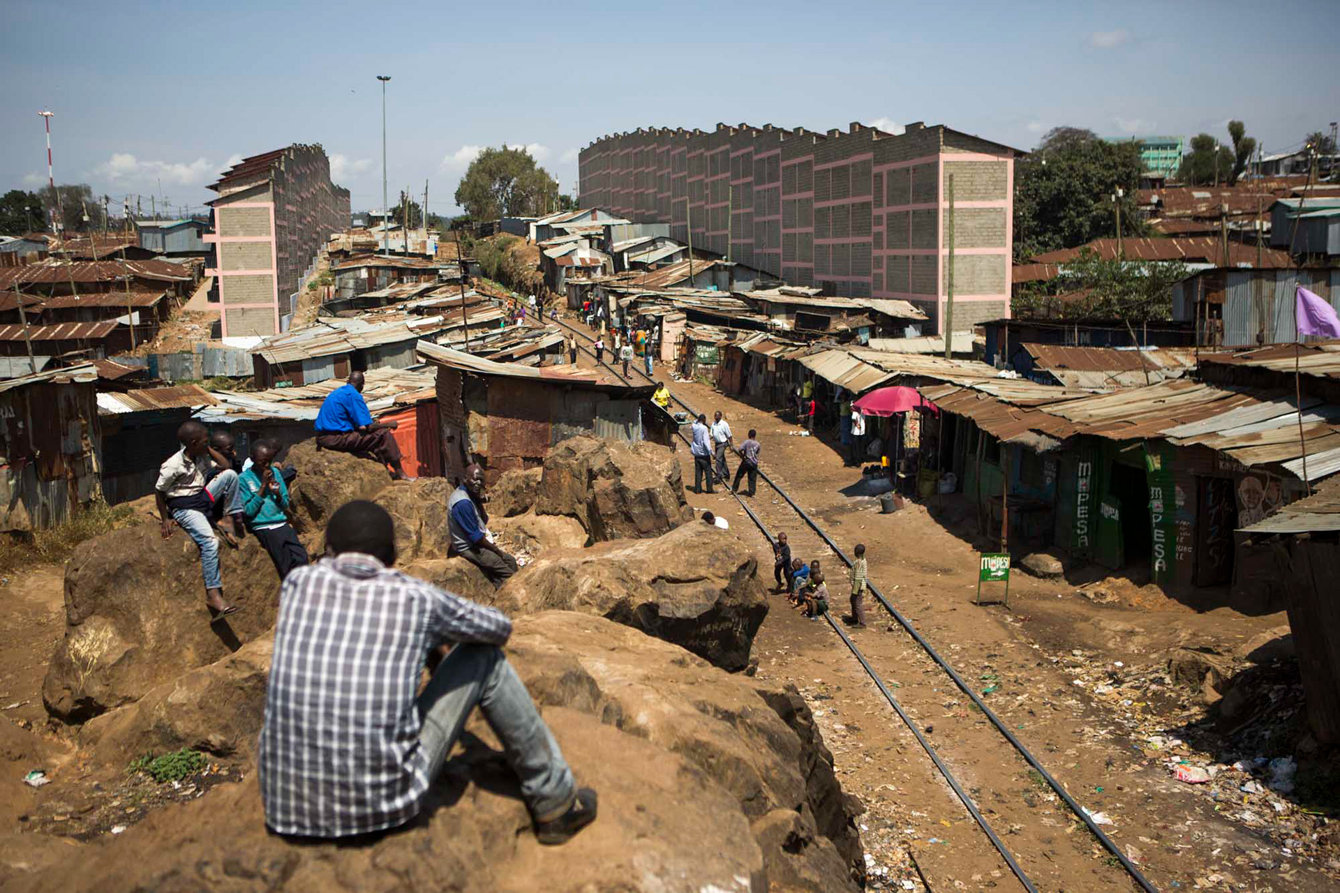 a man watches the train tracks in kibera, nairobi