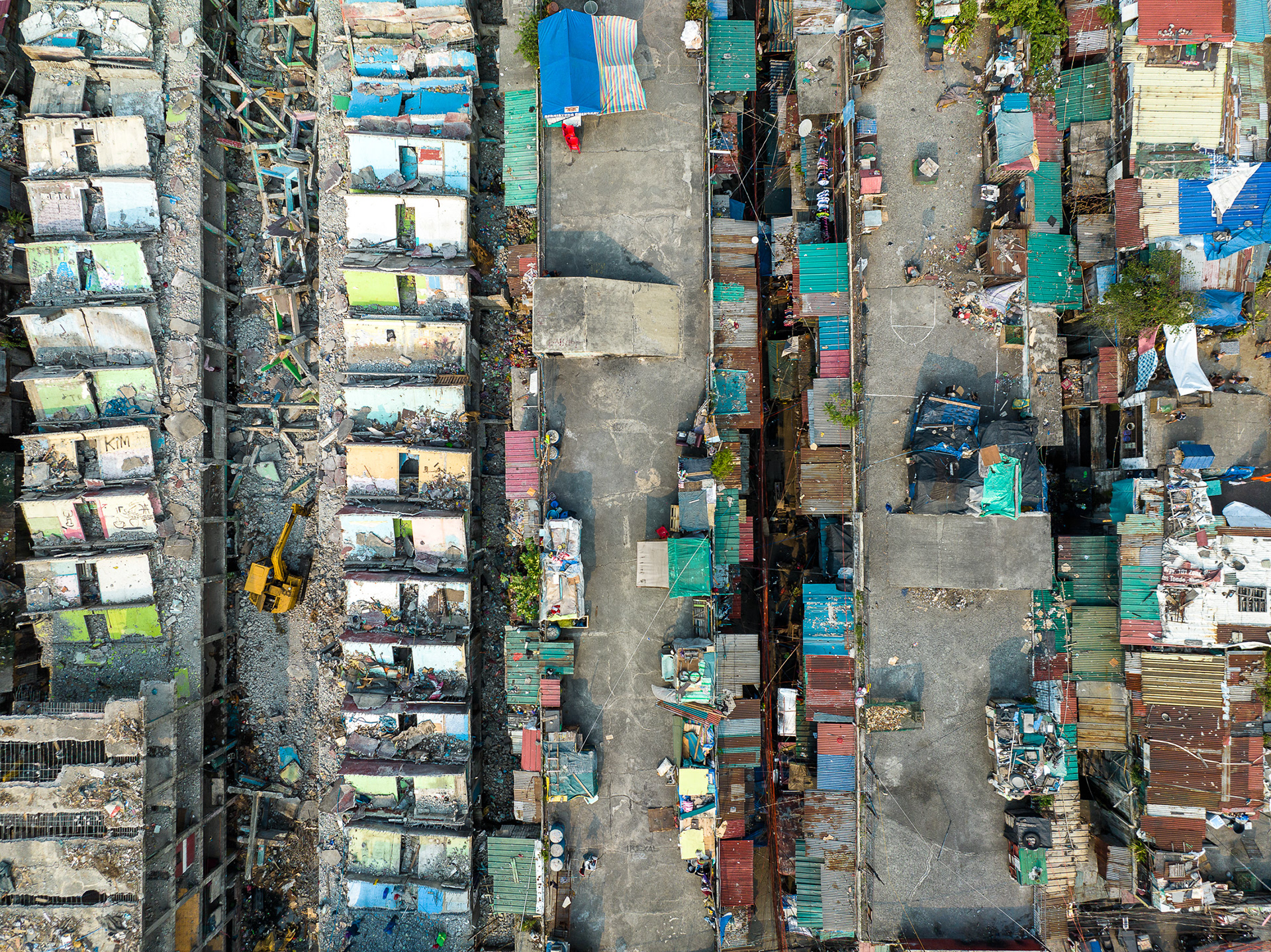 Manila housing demolition site with cramped flats and new developments, showing urban transition and inequality.