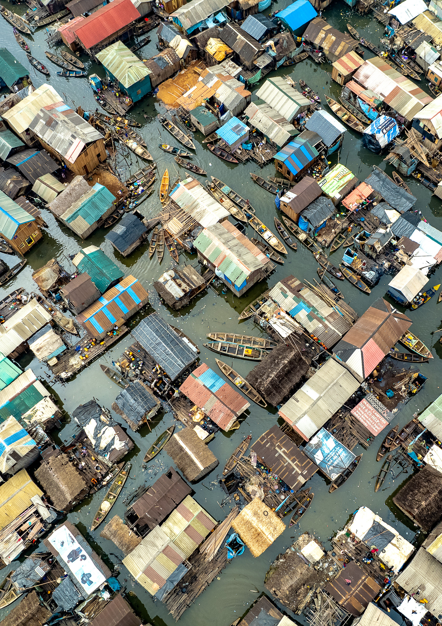 An aerial view of a floating slum, with houses and canoes.