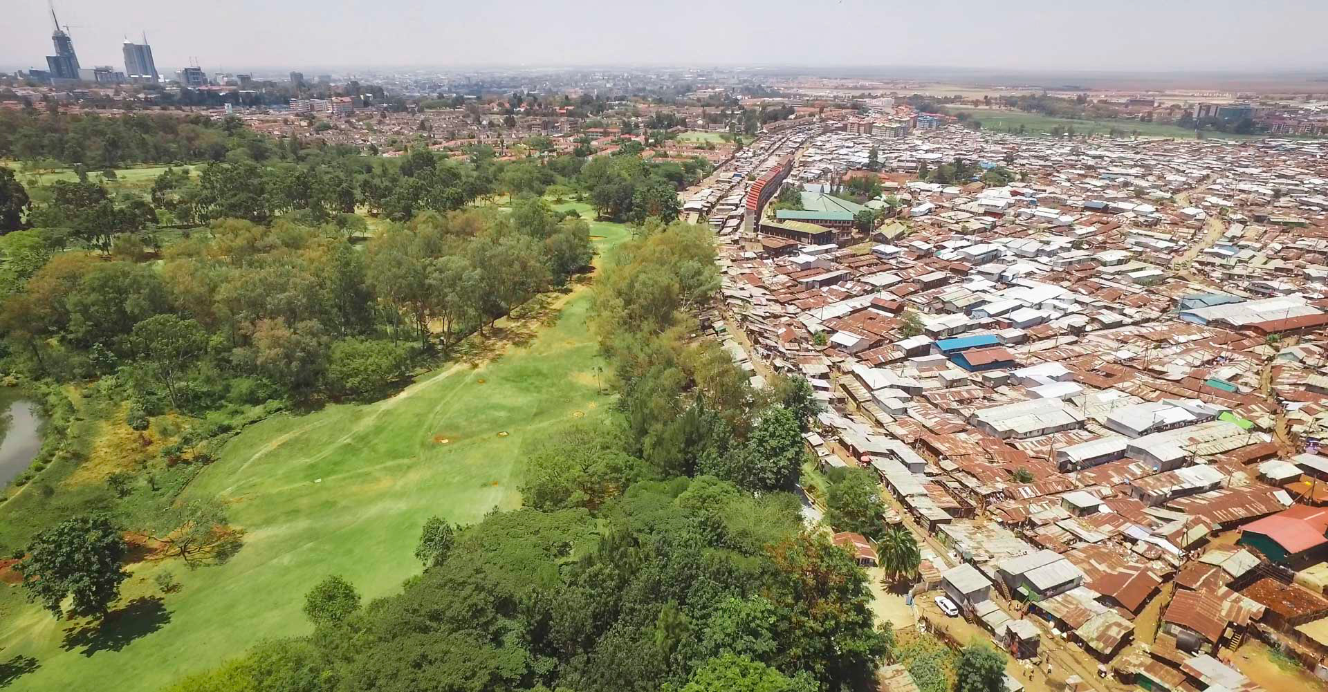 a golf course next to a slum with downtown skyscrapers in nairobi