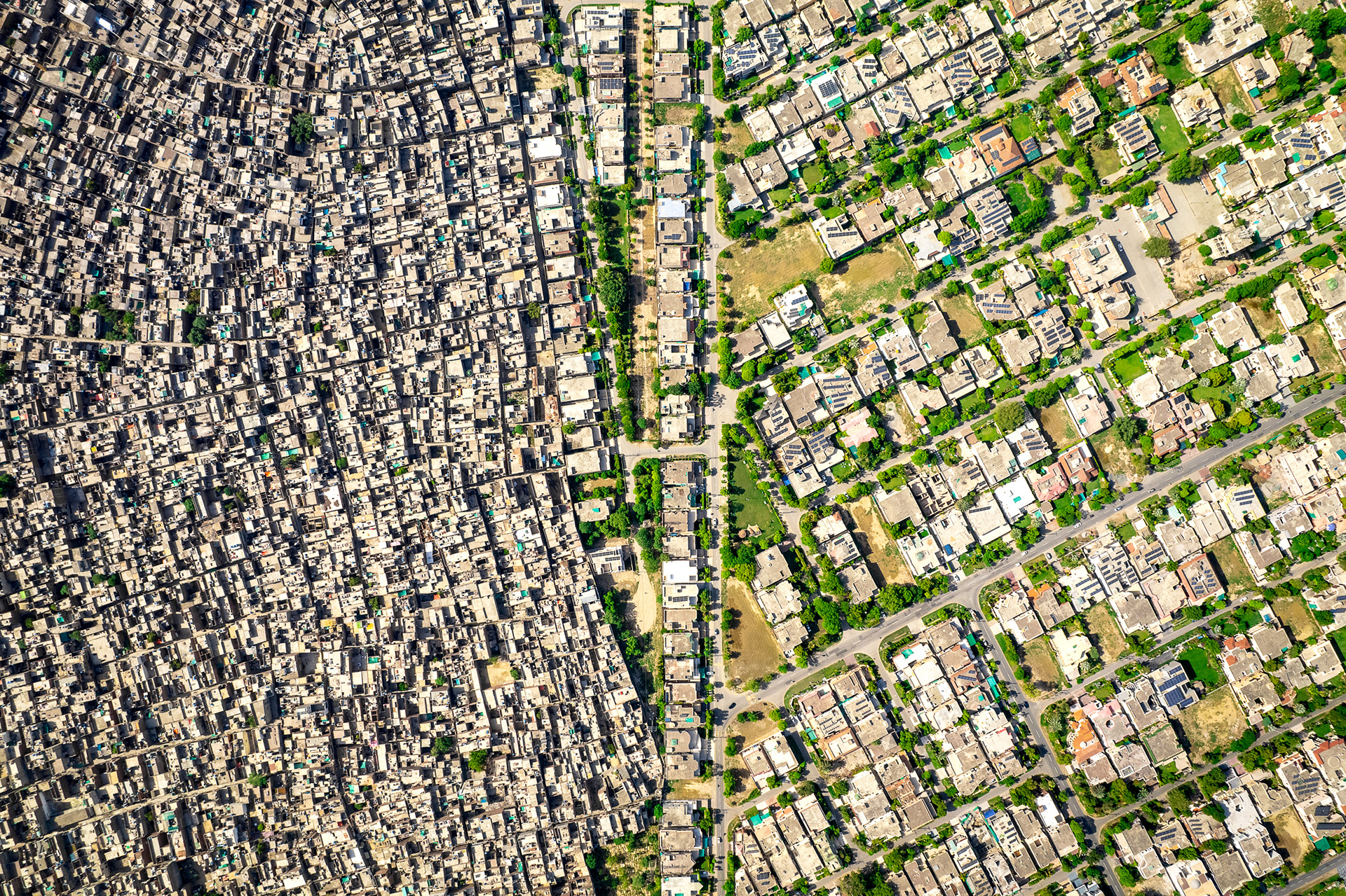 A drone view of a dense slum next to large homes.