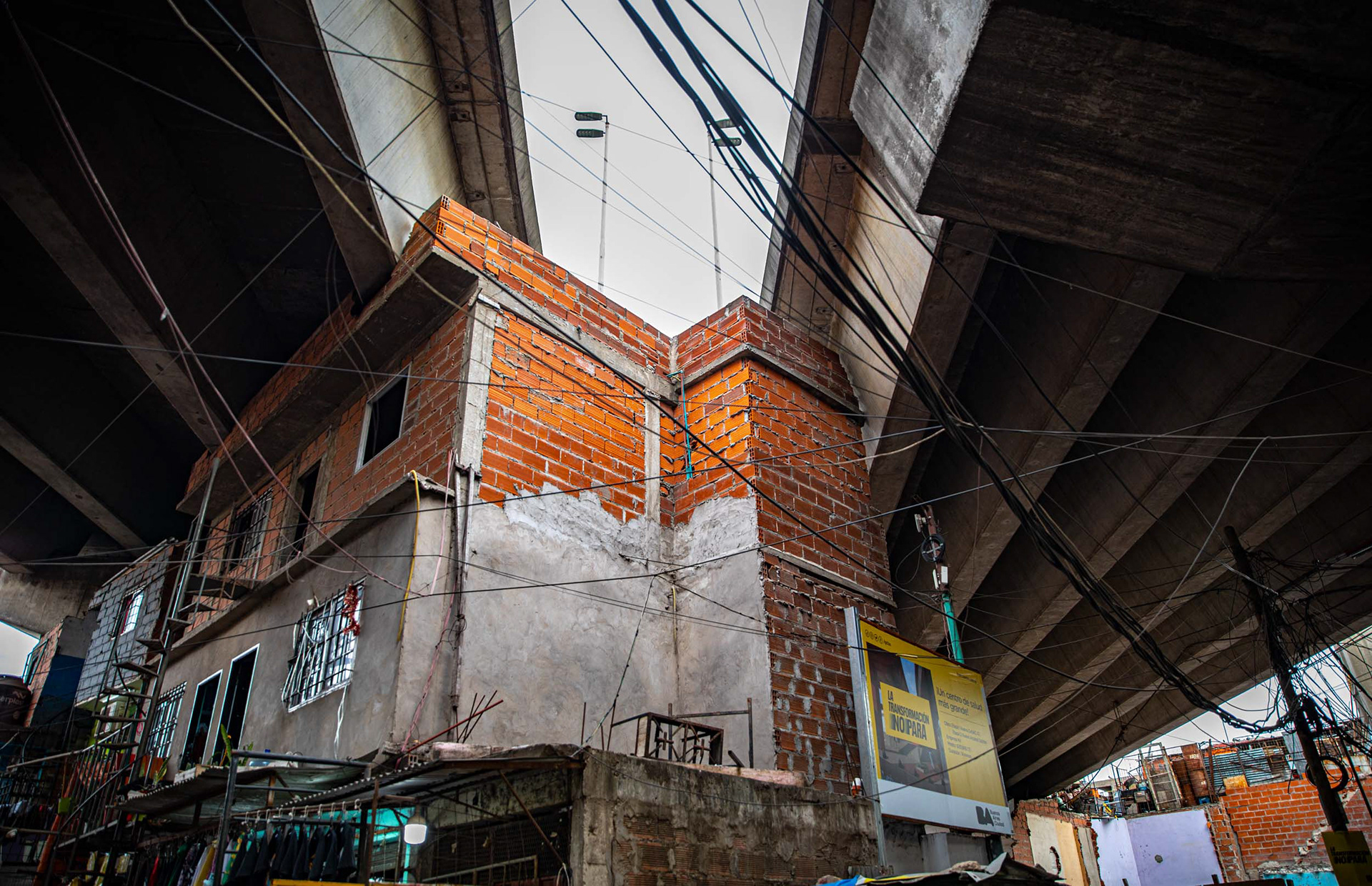An orange brick home underneath a highway.