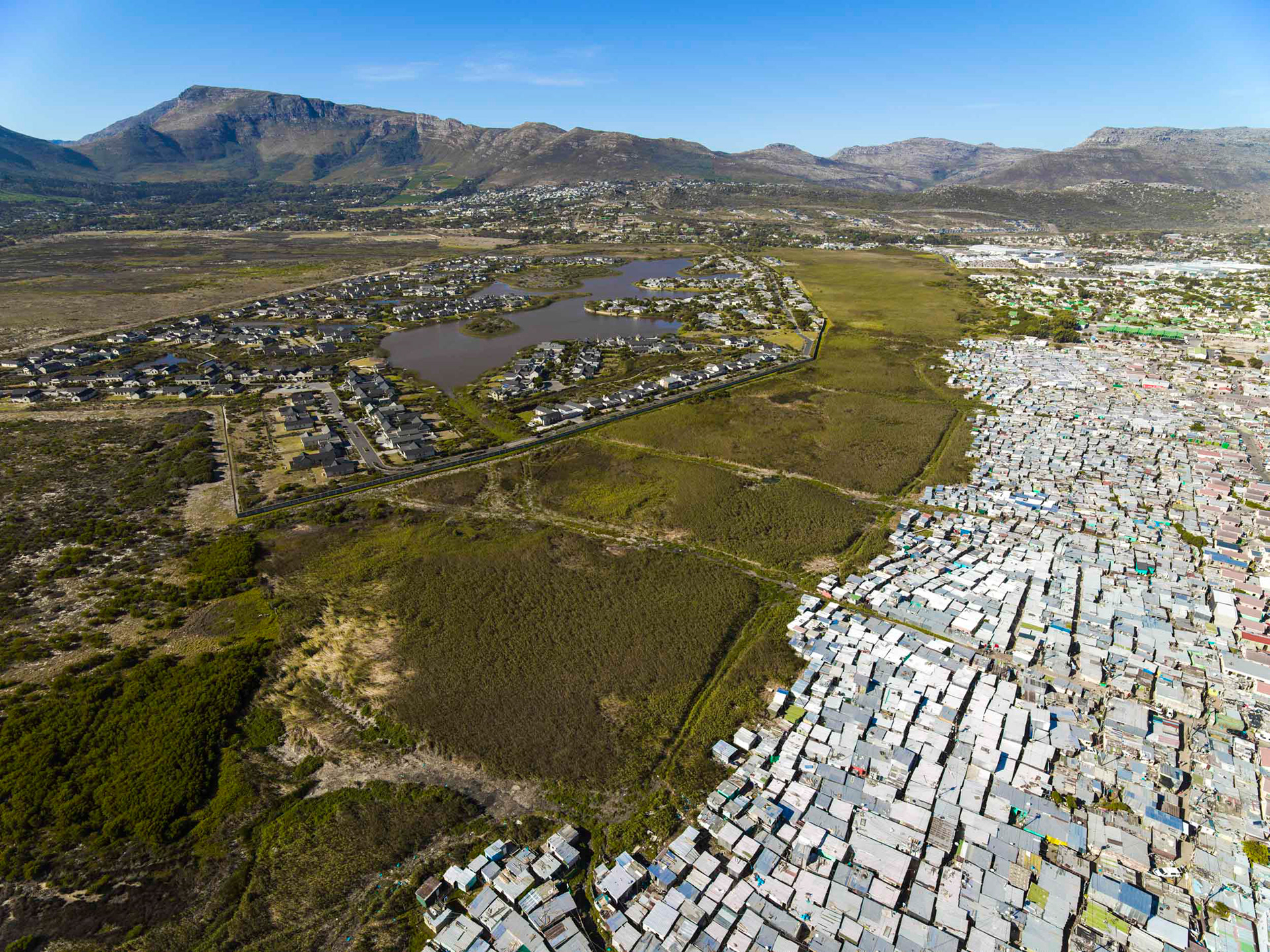 slums next to a lake with wealthy homes in cape town